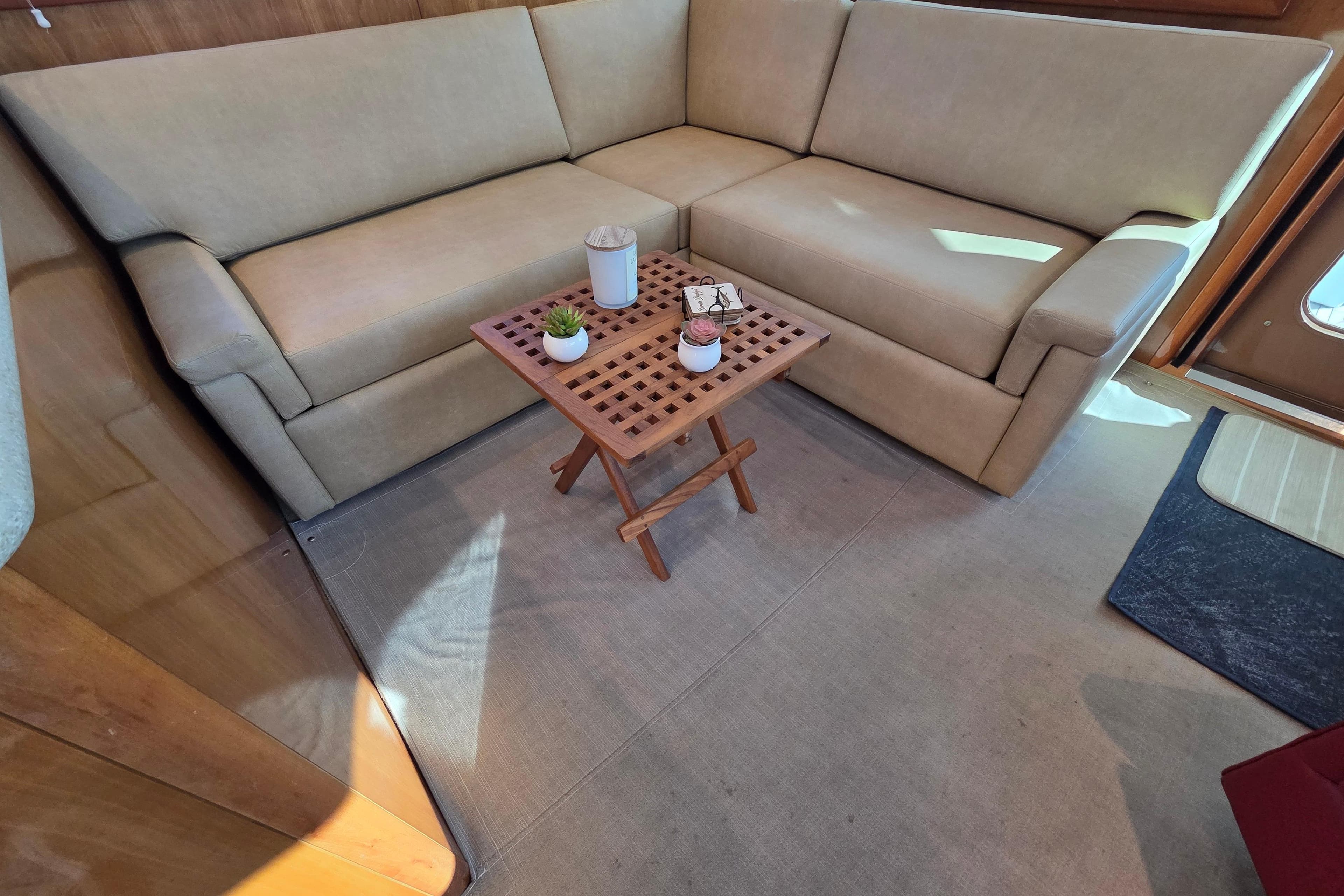 Luxurious interior of 2006 Hatteras 50 Convertible yacht with beige sofa and wooden table.
