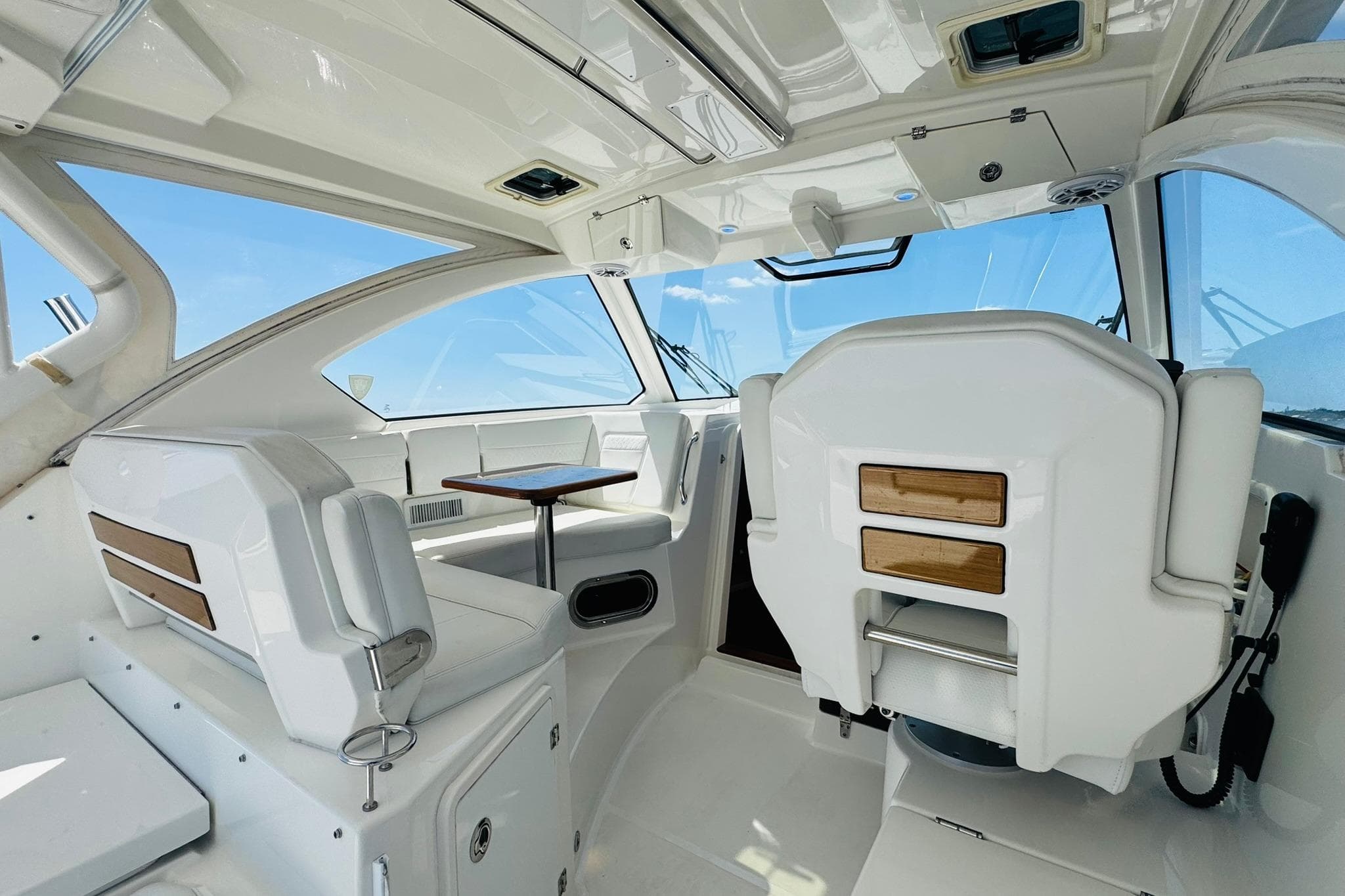 Interior of 2021 Pursuit OS 355 Offshore boat, featuring sleek white seating and wooden accents.