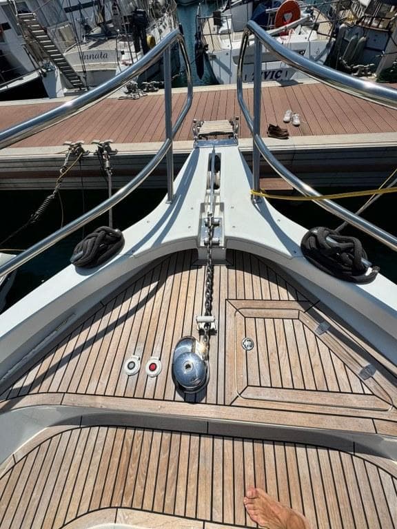Bow of 2022 Rodman 1290 Evolution yacht with wooden deck and metal railings.