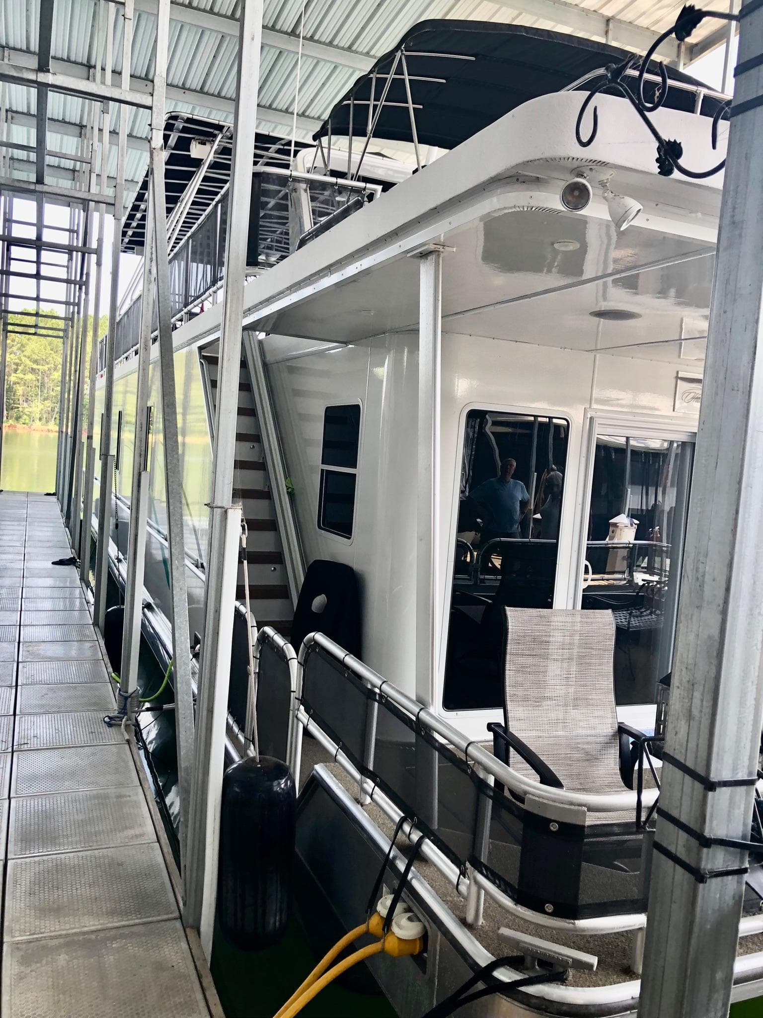 2016 Thoroughbred 67x17 houseboat docked in a covered marina.