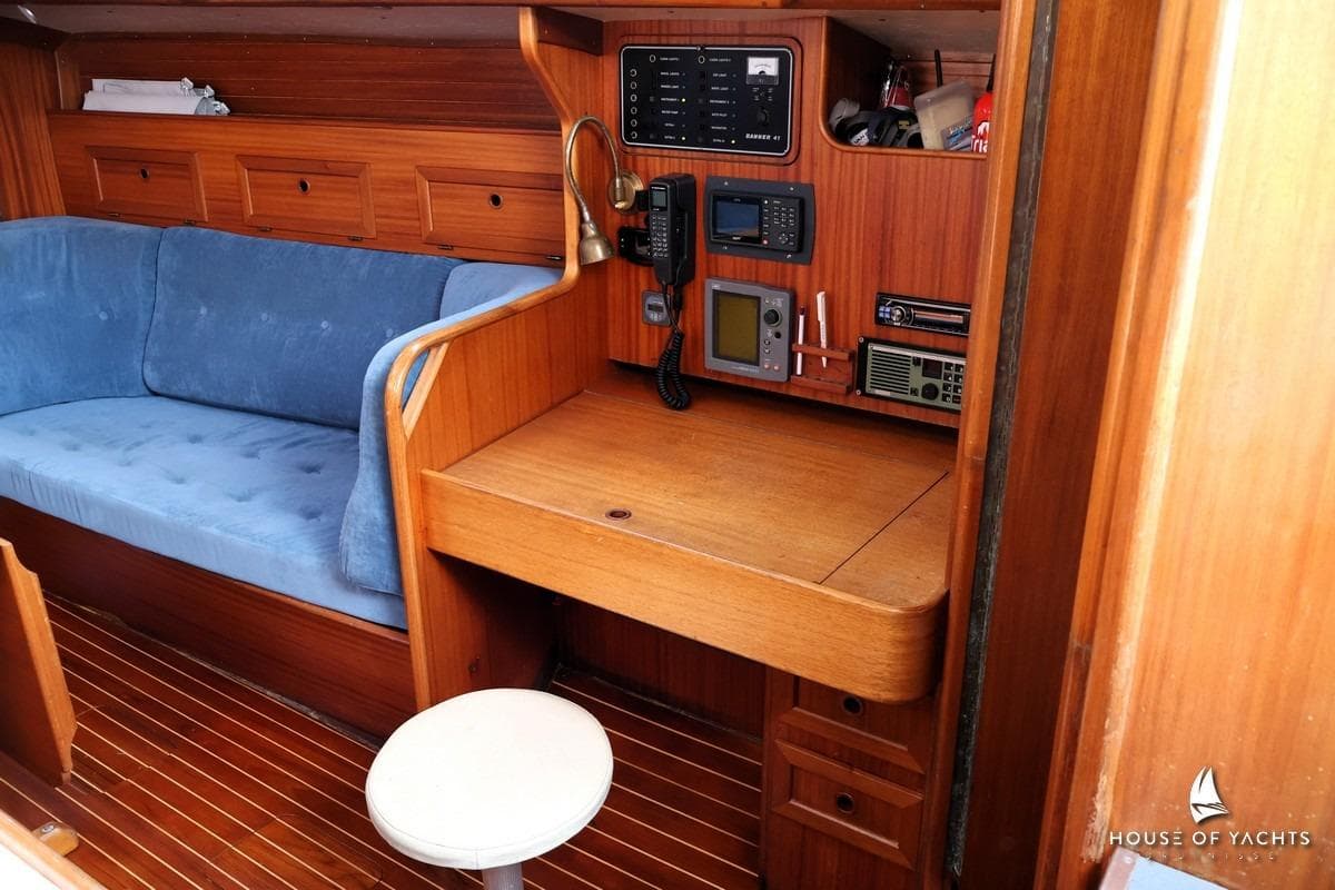 Cozy yacht interior with wooden desk, blue sofa, and navigation equipment, Banner 41, 1991.