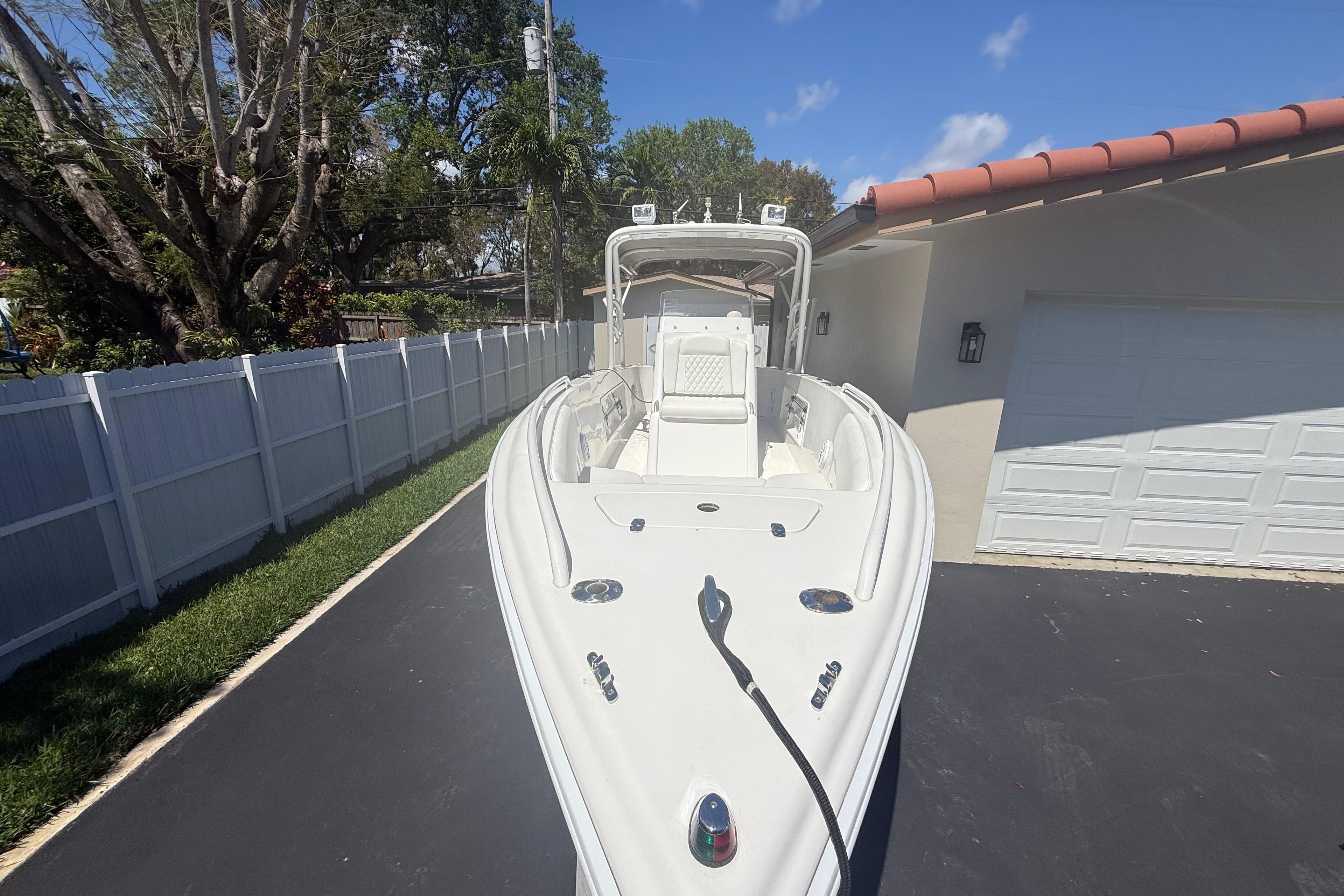 White Concept 27 boat from 2015 parked on a driveway beside a house.