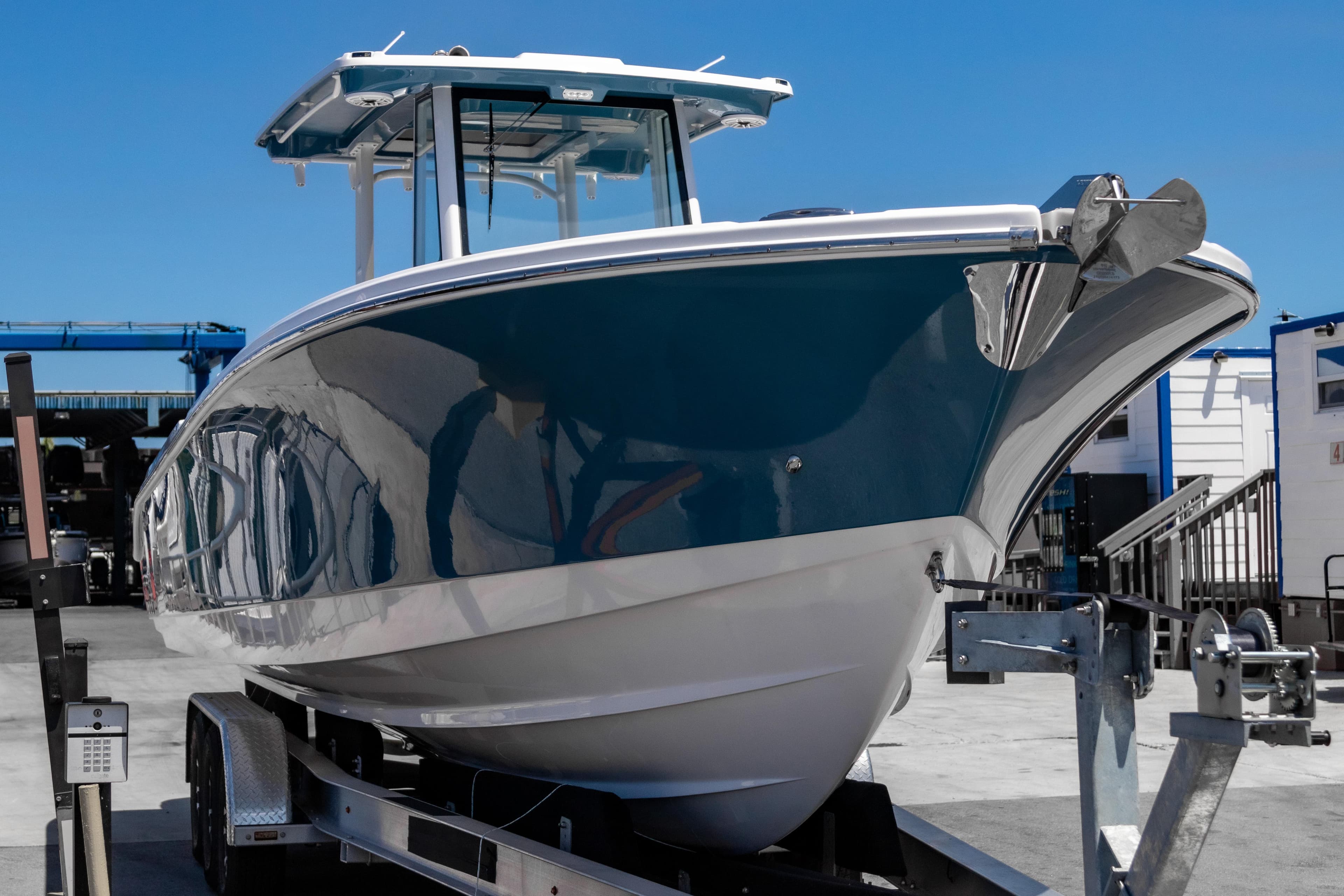 2025 Edgewater 325CC boat on trailer, sleek design, blue hull, sunny day.