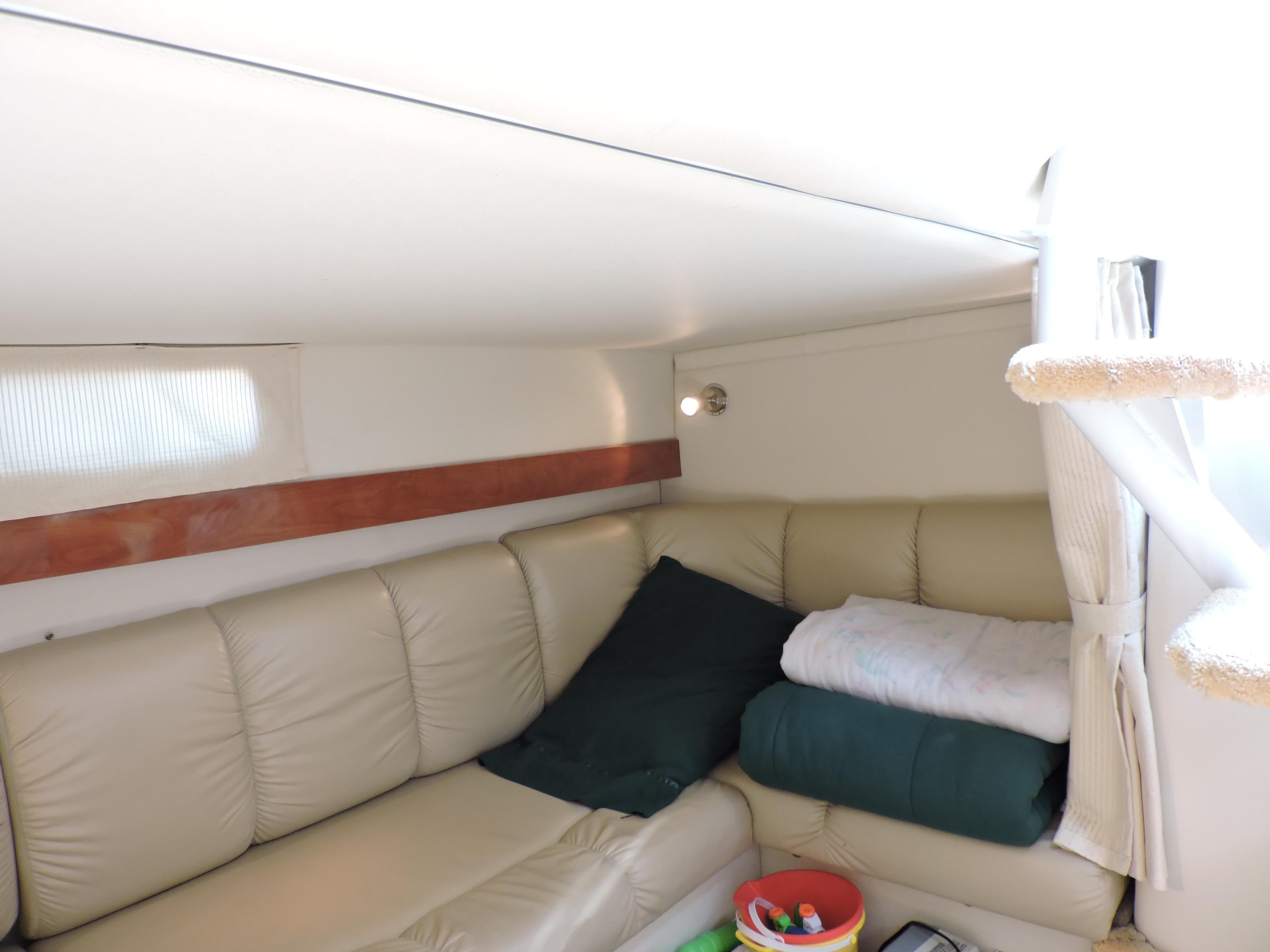 Interior of 2005 Larson 330 CABRIO boat with beige leather seating and cozy cushions.