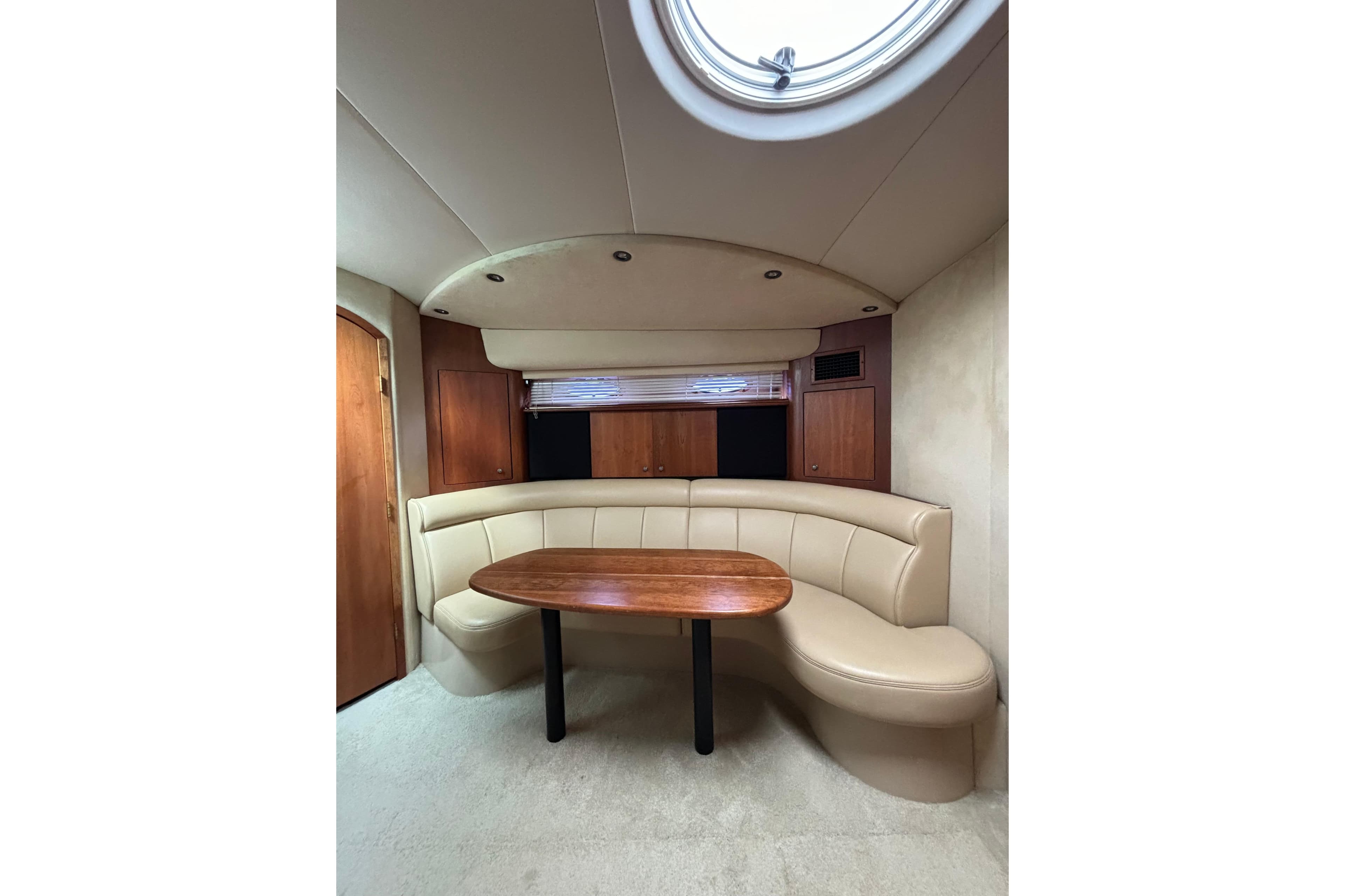 Interior of 2000 Cruisers 3870 yacht with curved seating and wooden table.