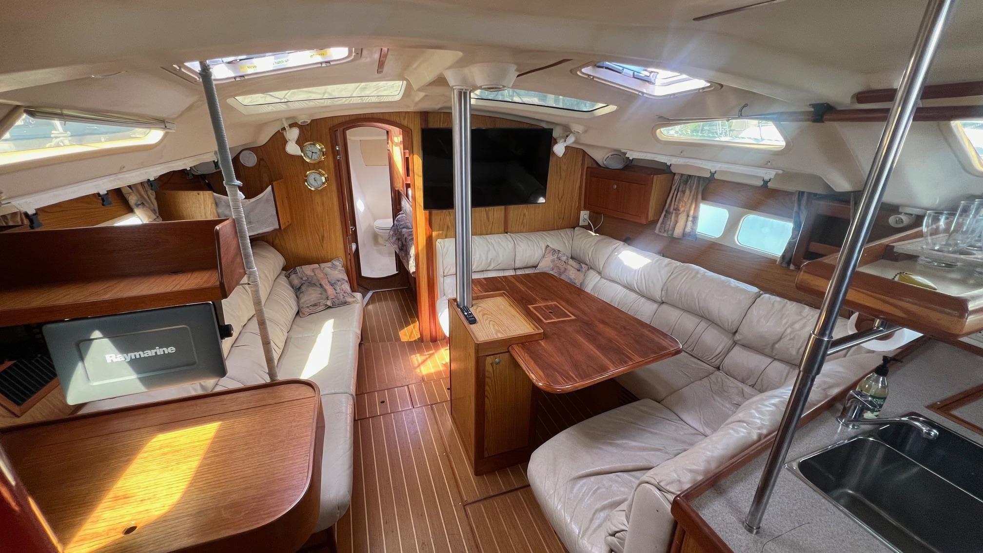 Spacious interior of 2000 Hunter 410 sailboat with cozy seating and wooden finishes.