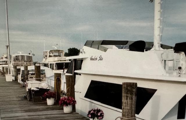 1990 Motor Yacht 70 Brata docked, surrounded by other boats and potted flowers.
