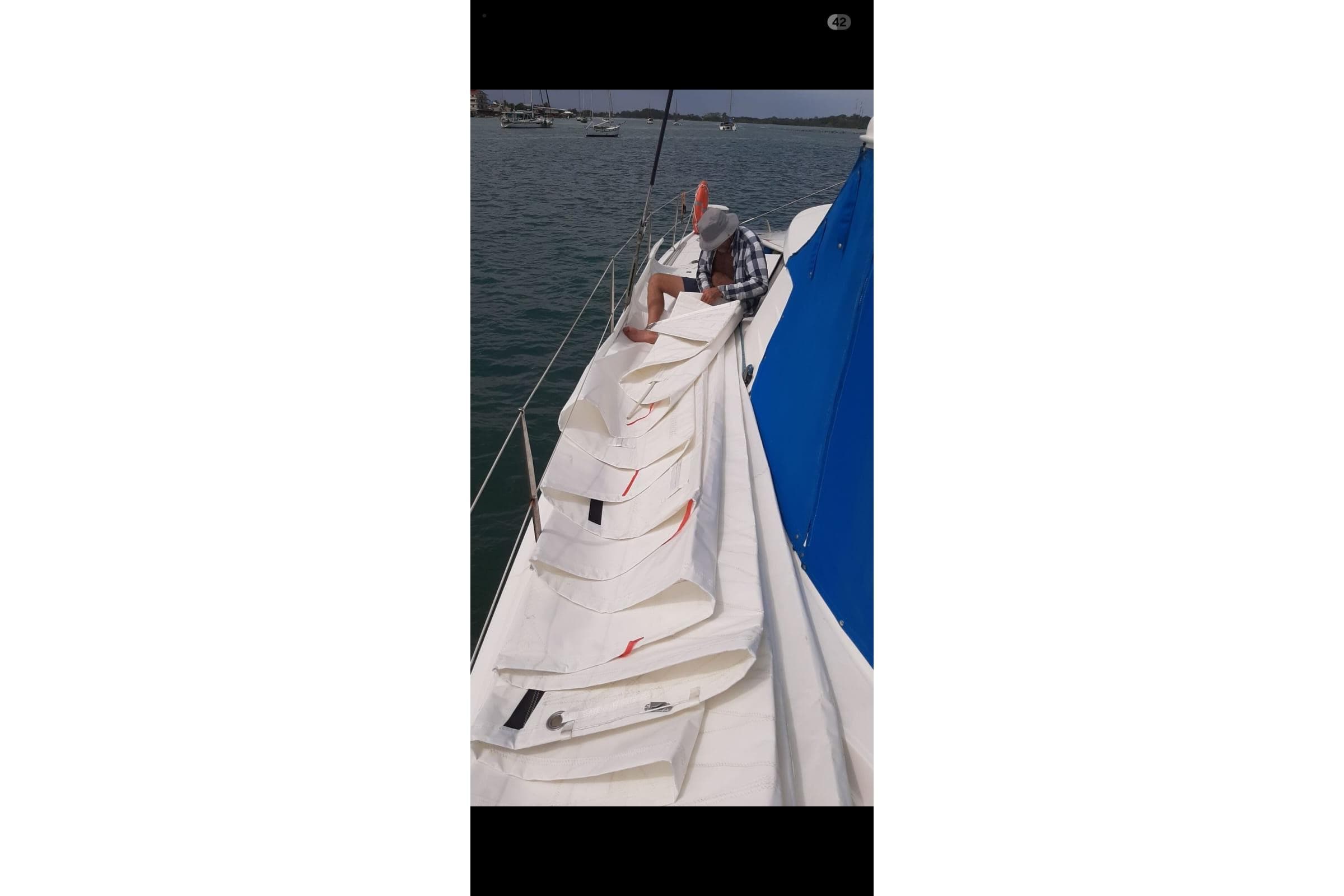 Person folding sail on 2003 Fountaine Pajot Belize 43 catamaran.