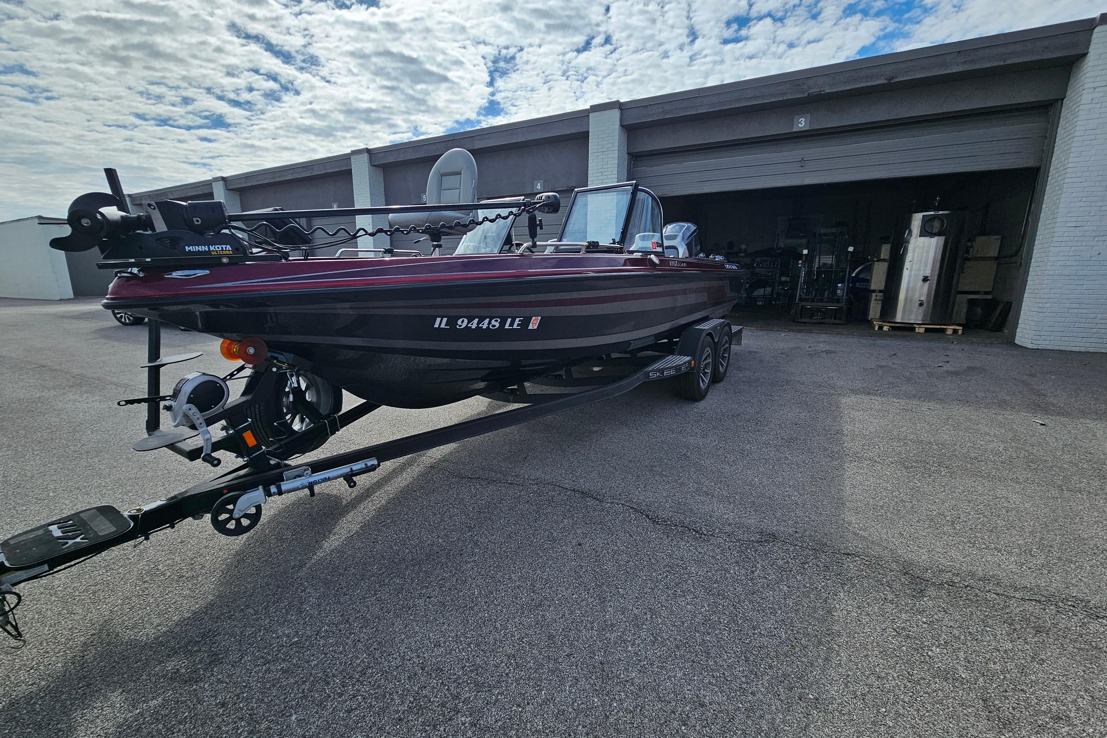 2023 Skeeter WX2200 boat on trailer outside a garage under a cloudy sky.