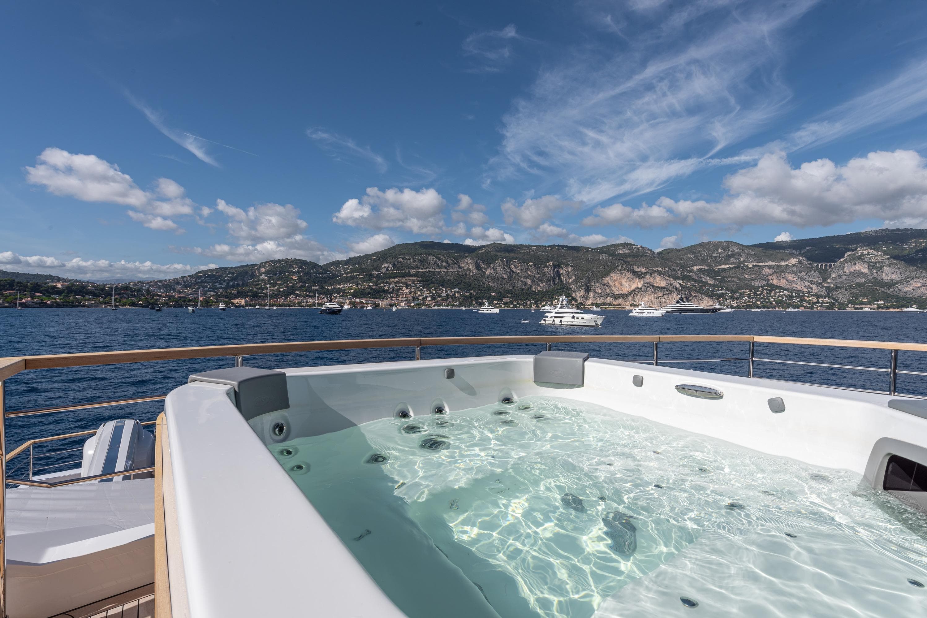 Luxurious 2025 Numarine 37XP yacht with jacuzzi, scenic ocean view, and mountainous backdrop.