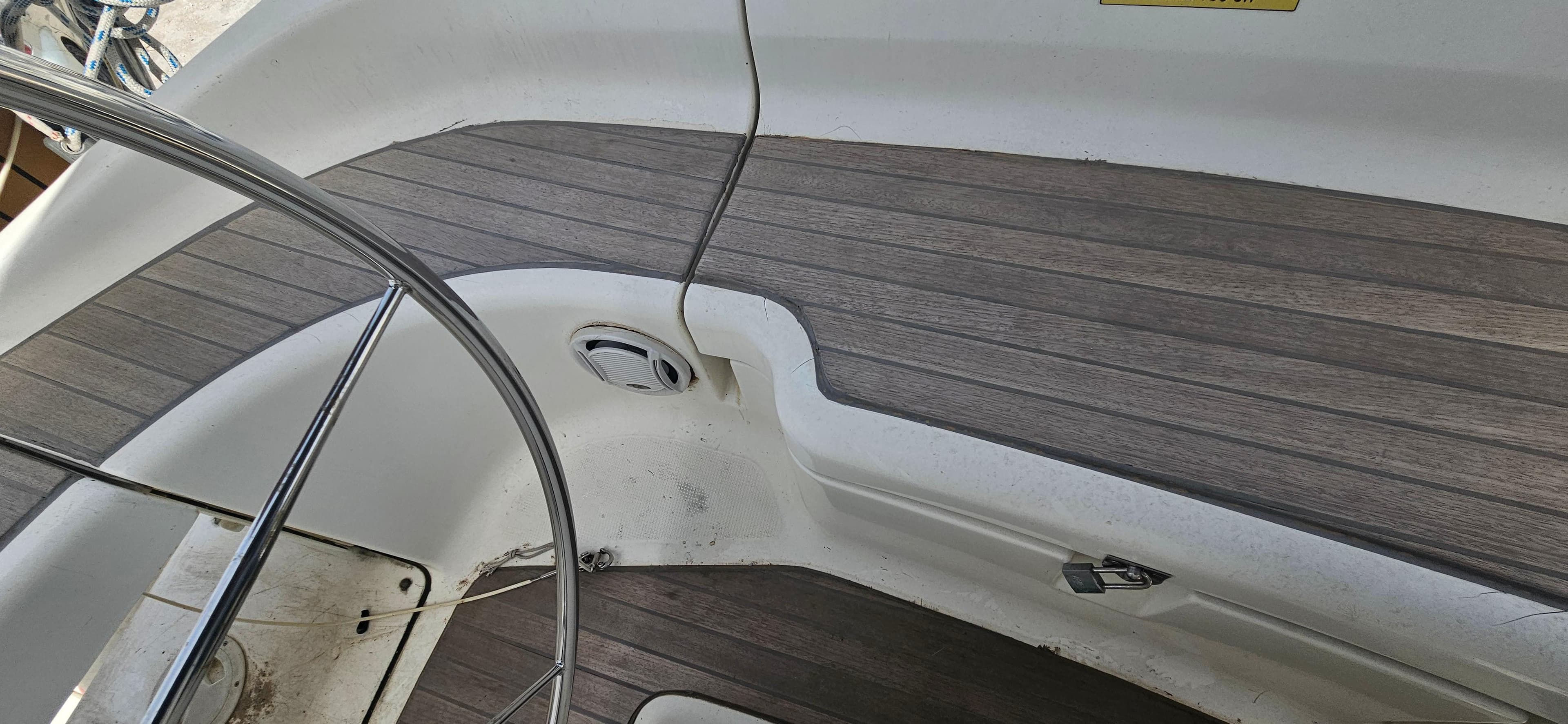 Cockpit of 2004 Bavaria 38 sailboat with wooden flooring and steering wheel.