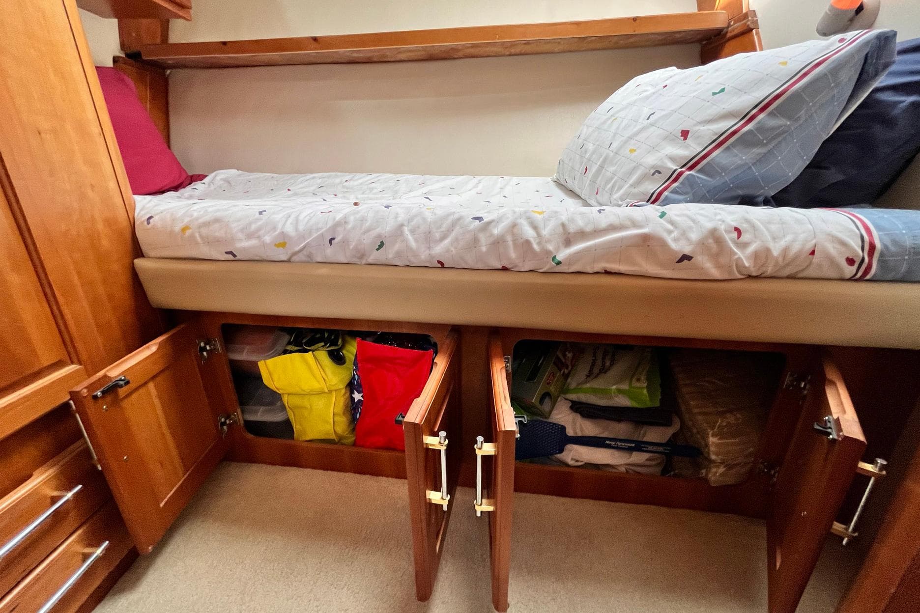 2003 Luhrs 40 Convertible cabin with storage under bed, featuring wooden cabinets and colorful bedding.