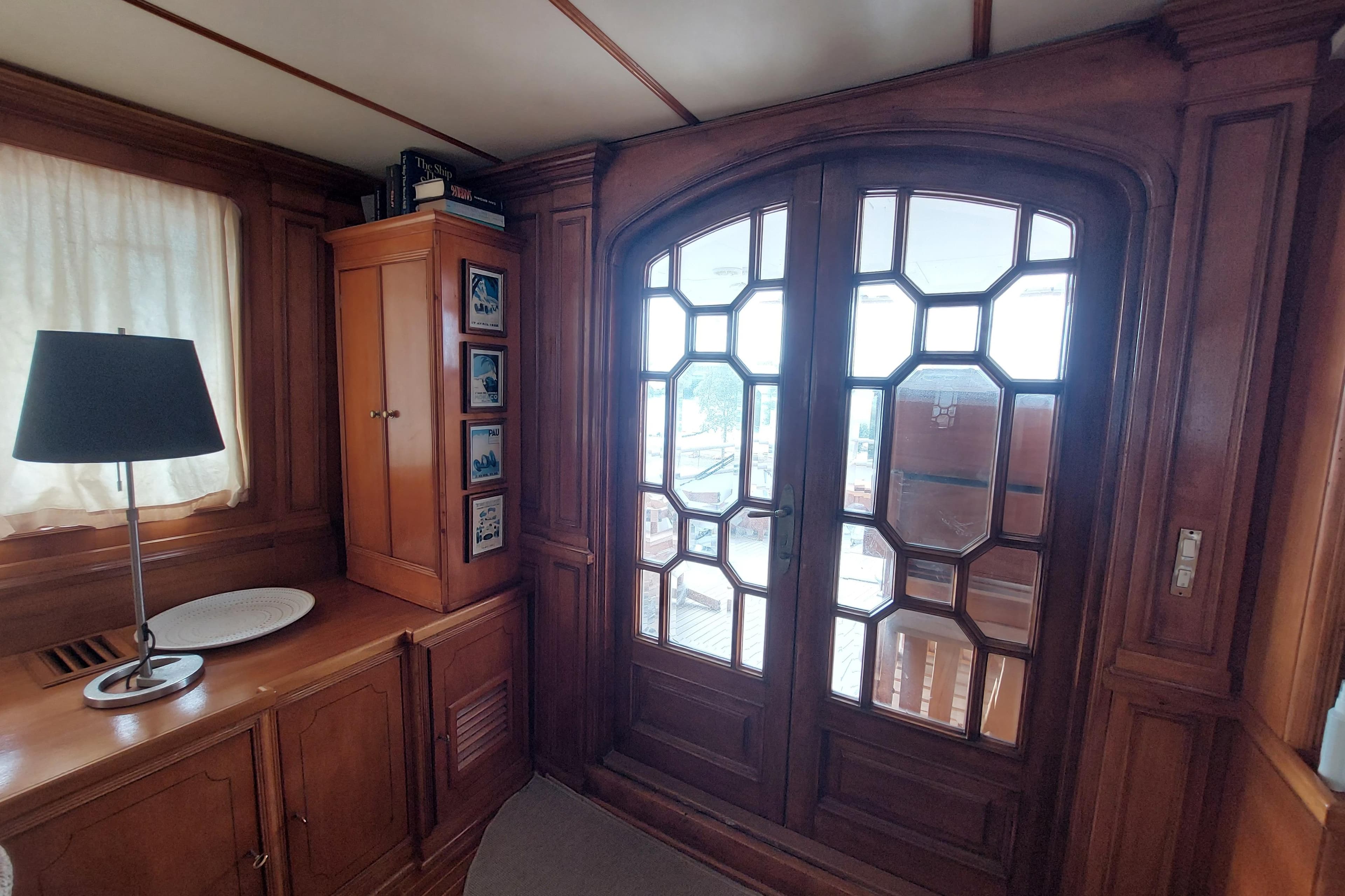 Luxurious wooden interior of a 1977 Codecasa 27m yacht with elegant glass doors.