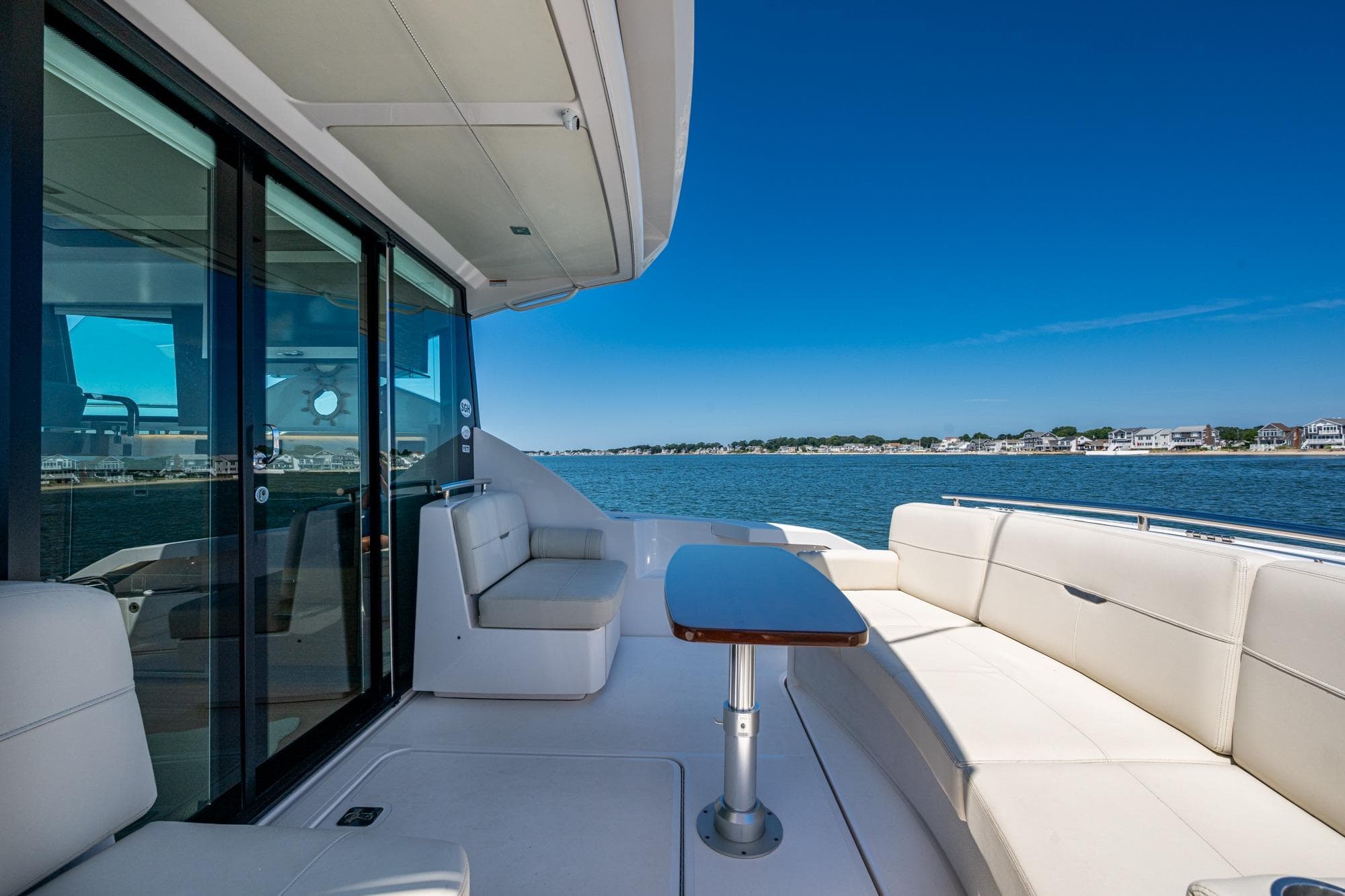 2020 Tiara Yachts C44 Coupe deck with seating, overlooking serene waters and shoreline.