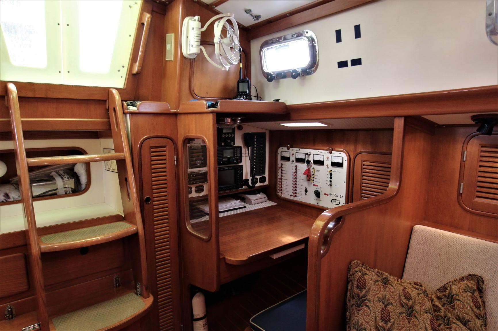 Interior of a 1986 Mason 33 sailboat with wooden cabinetry and navigation station.
