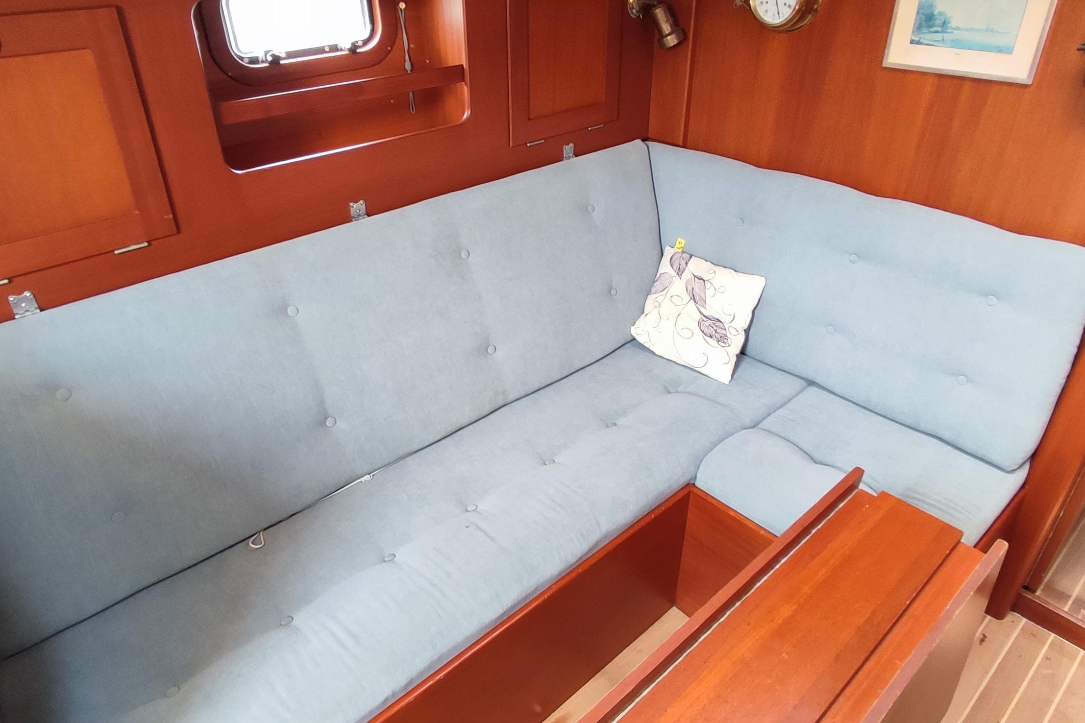 Interior of 1982 Hallberg-Rassy 352 yacht with blue cushioned seating and wooden paneling.