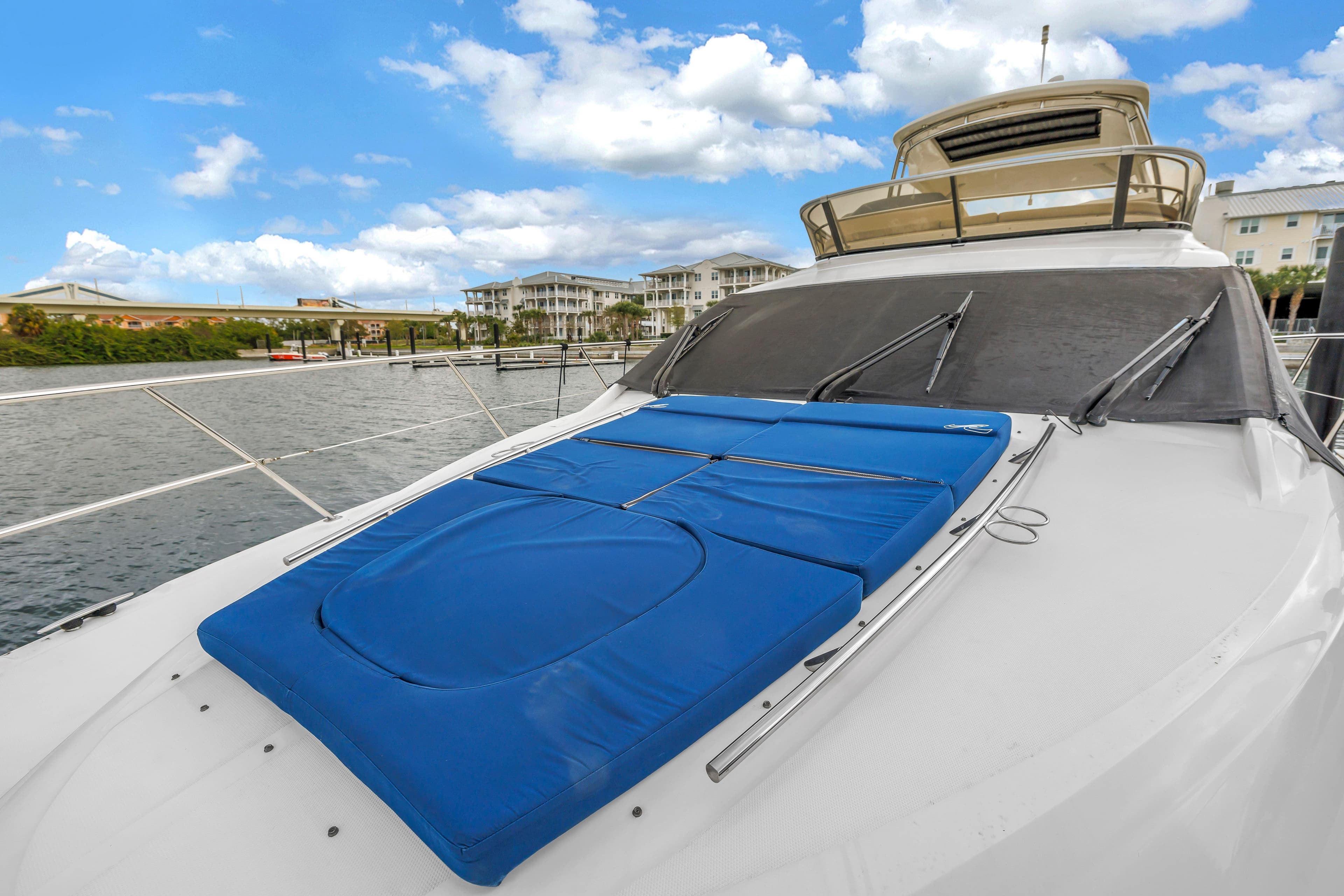 2016 Sea Ray 510 Fly yacht with blue sun pads on deck, docked by waterfront.
