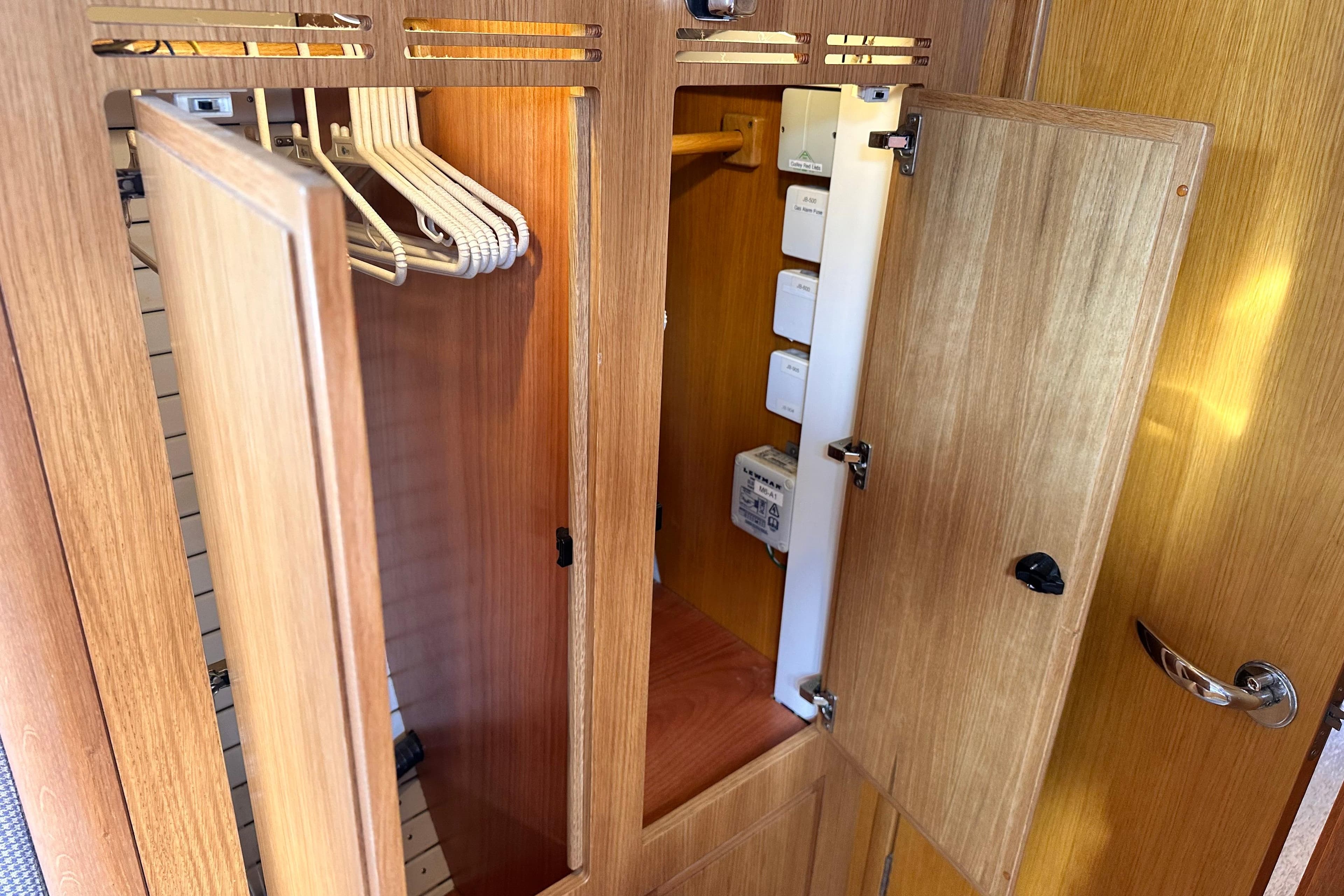 2019 Hallberg-Rassy 44 yacht interior closet with wooden finish and hangers.
