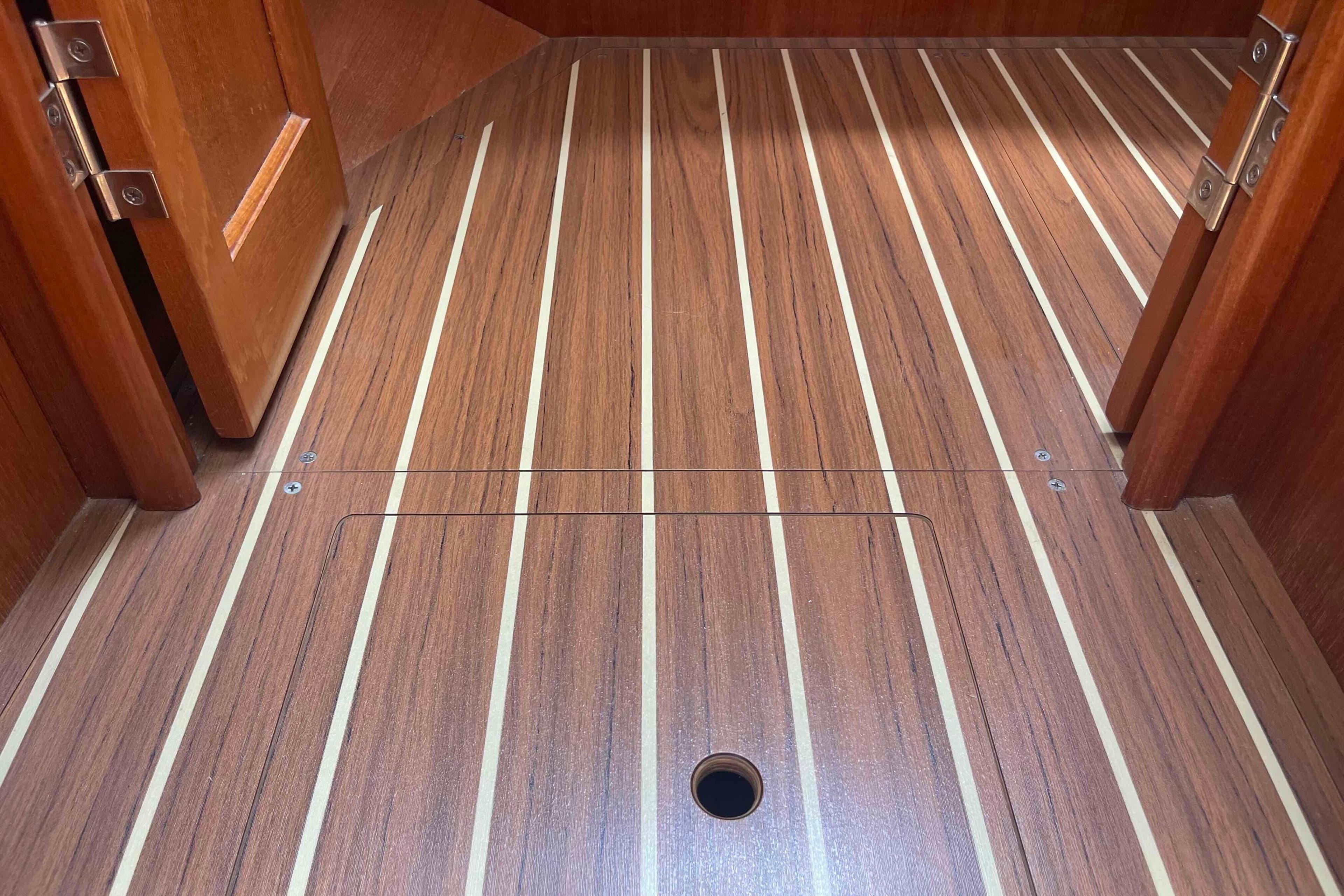 Wooden interior flooring of a 2004 Hunter 36 sailboat, featuring striped design and hatch access.