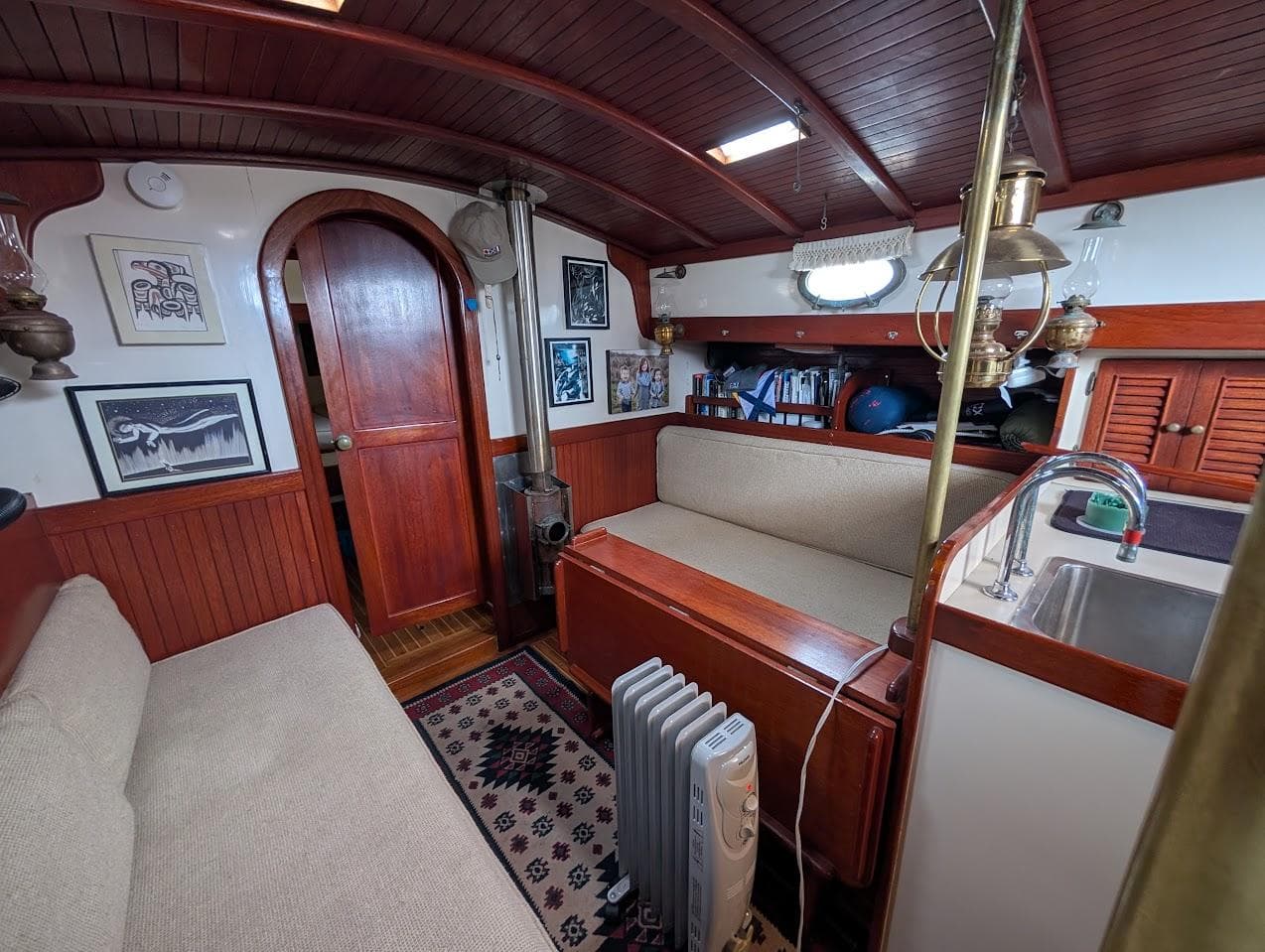 Interior of 1977 Alajuela 38 Mk1 sailboat with wooden furnishings and cozy seating area.