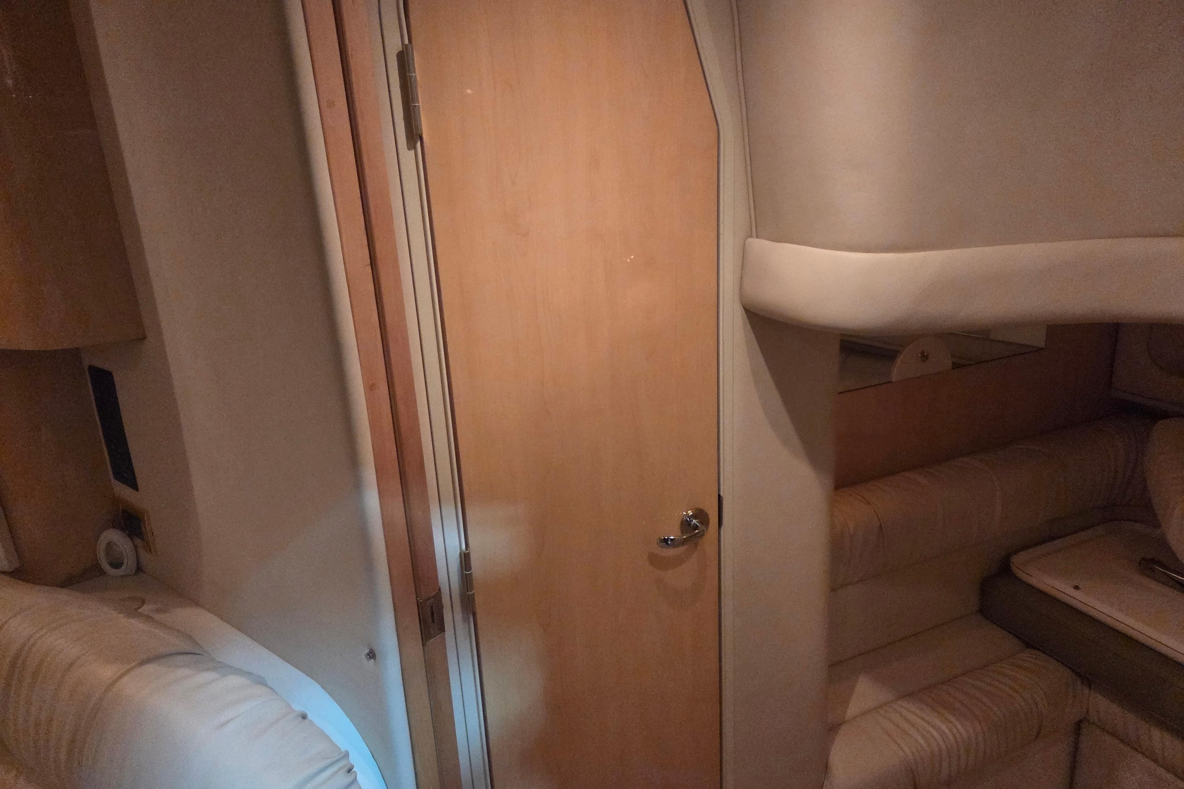 Interior cabin of 2000 Sea Ray 410 Sundancer yacht with wooden door and seating.