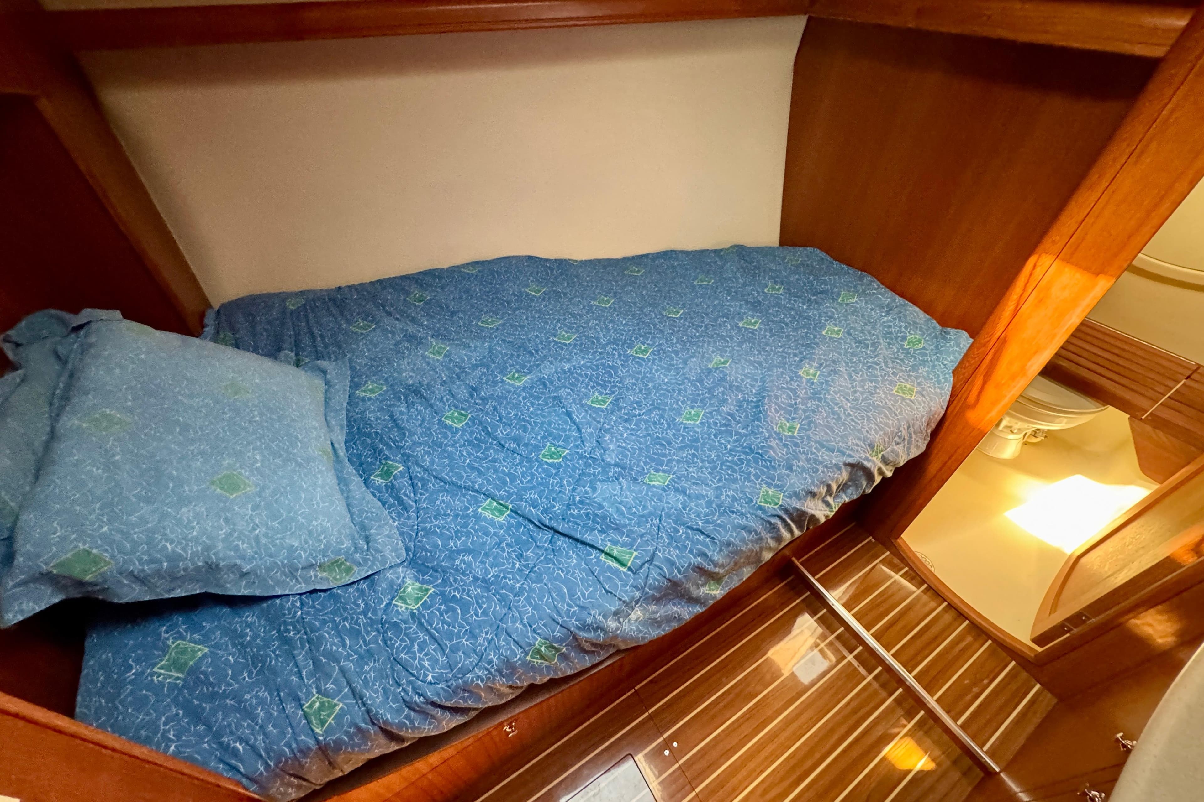 Cozy cabin interior of 2007 Hunter 41 Deck Salon with blue bedding and wooden accents.