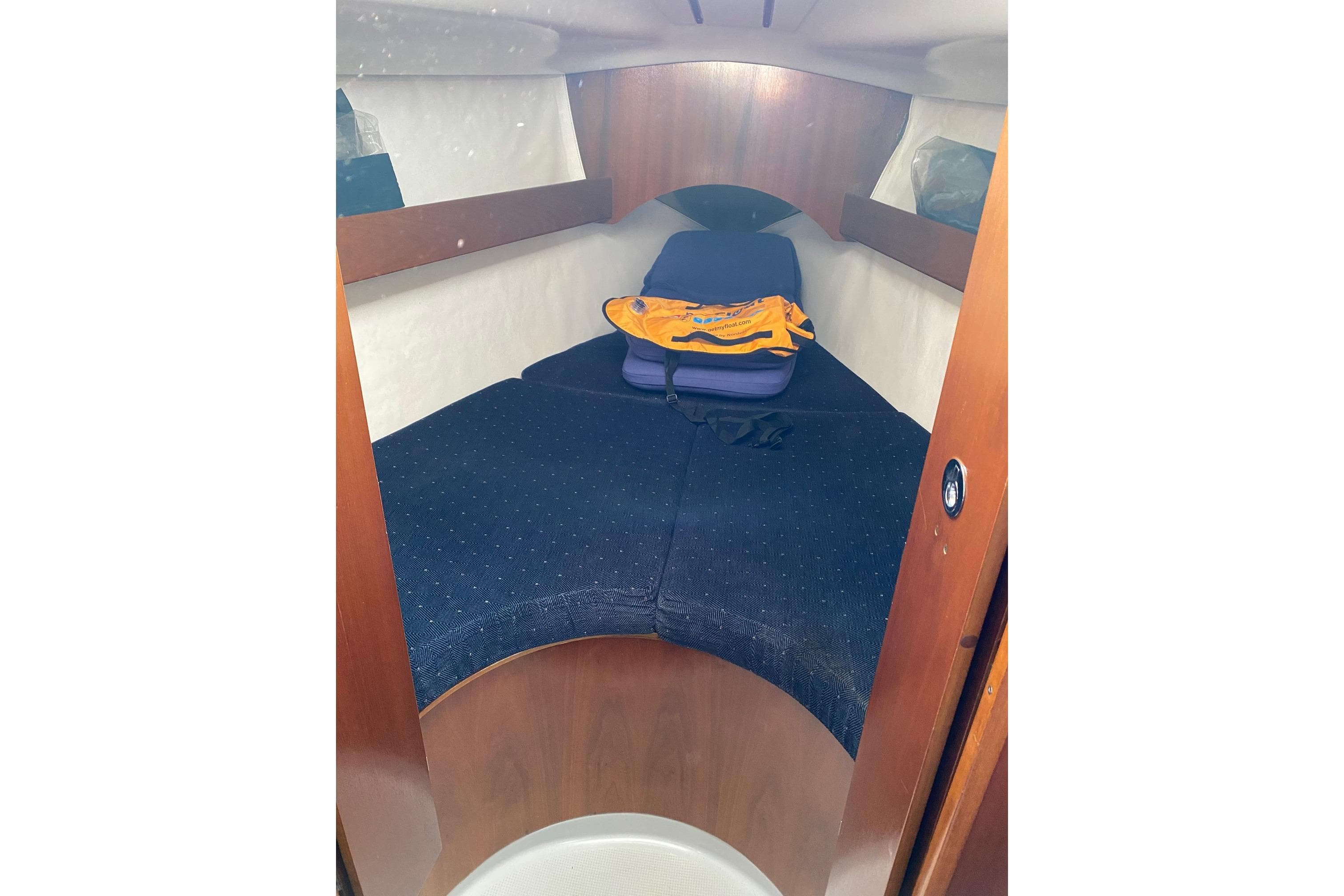 Cozy cabin interior of a 1992 Beneteau First 310 sailboat with blue cushions.