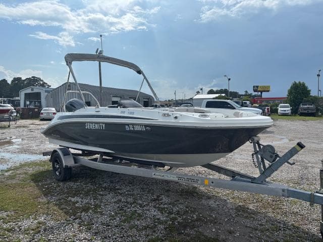 2022 Hurricane SunDeck Sport 185 OB boat on trailer, parked outdoors under cloudy sky.