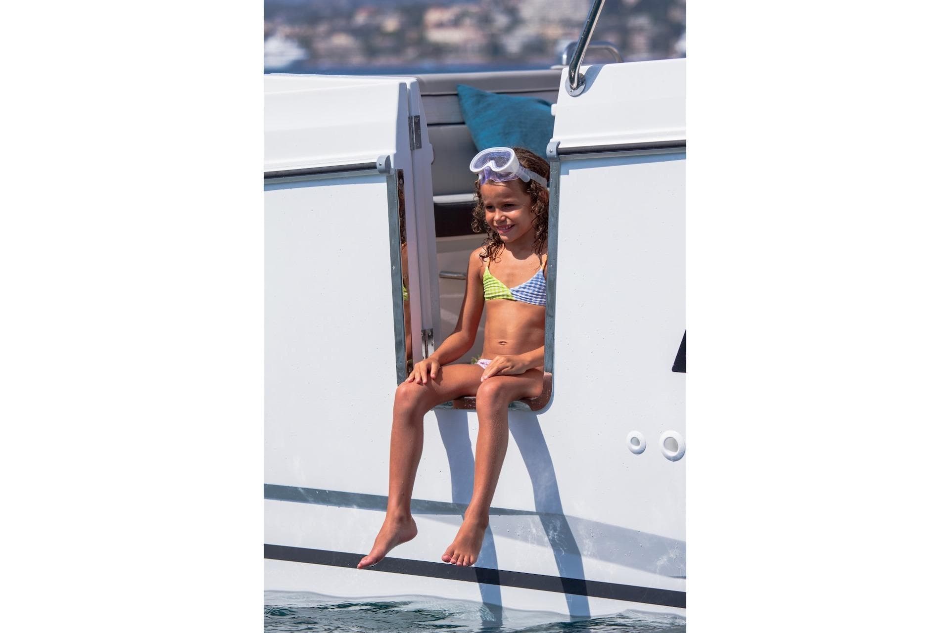 Young girl sitting on Jeanneau NC 895 Series 2 boat, enjoying a sunny day.