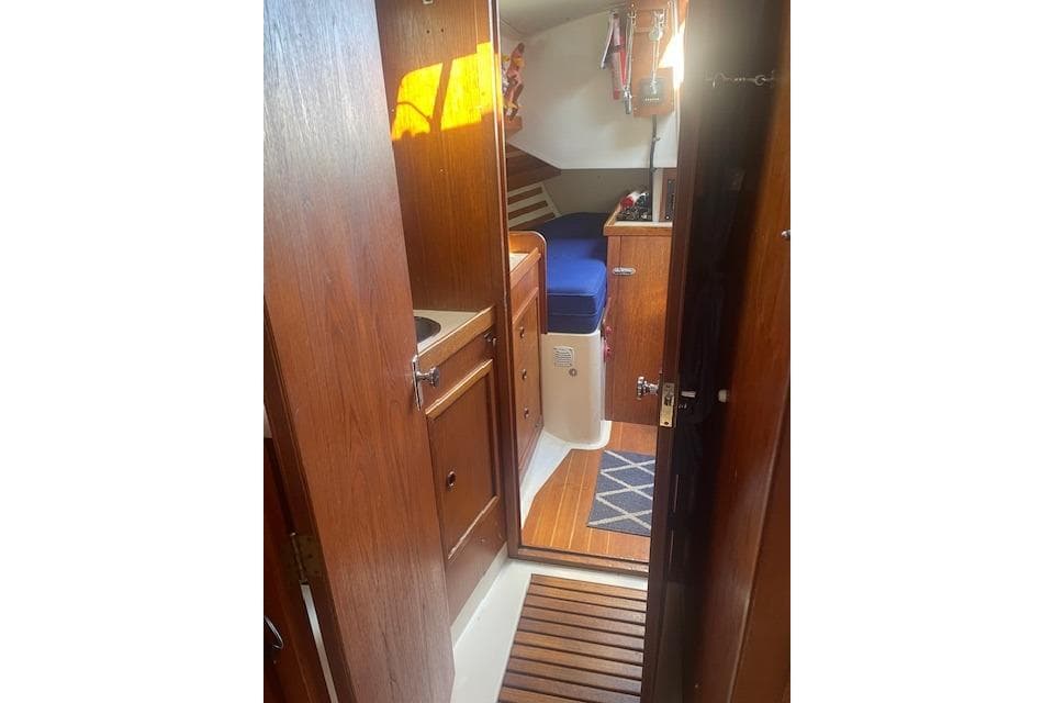 Interior of 1978 Hinterhoeller Niagara 35 Classic sailboat with wooden cabinetry and blue seating.