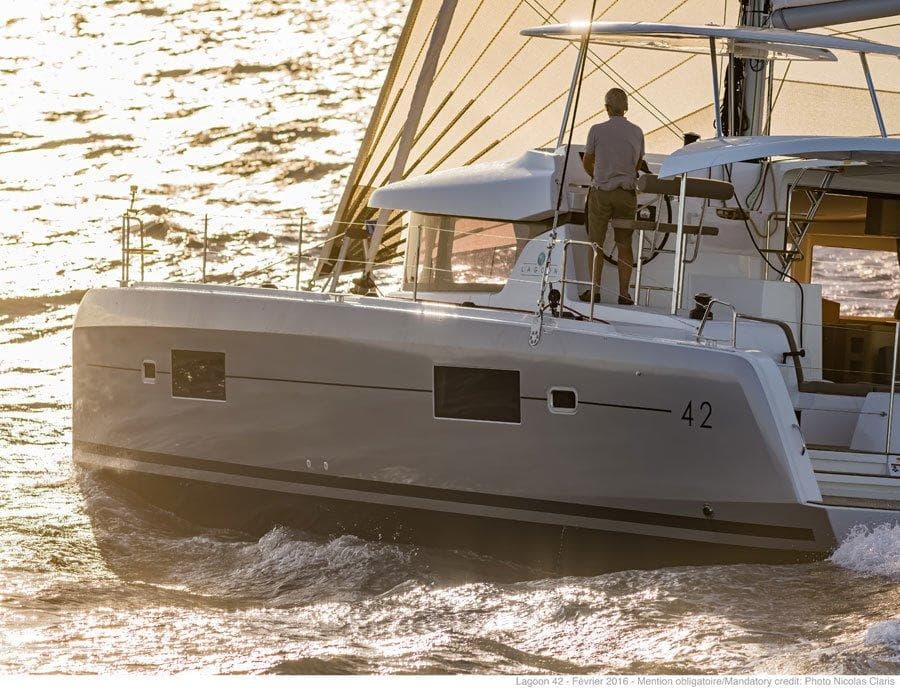 2024 Lagoon 42 sailing catamaran on the water at sunset.