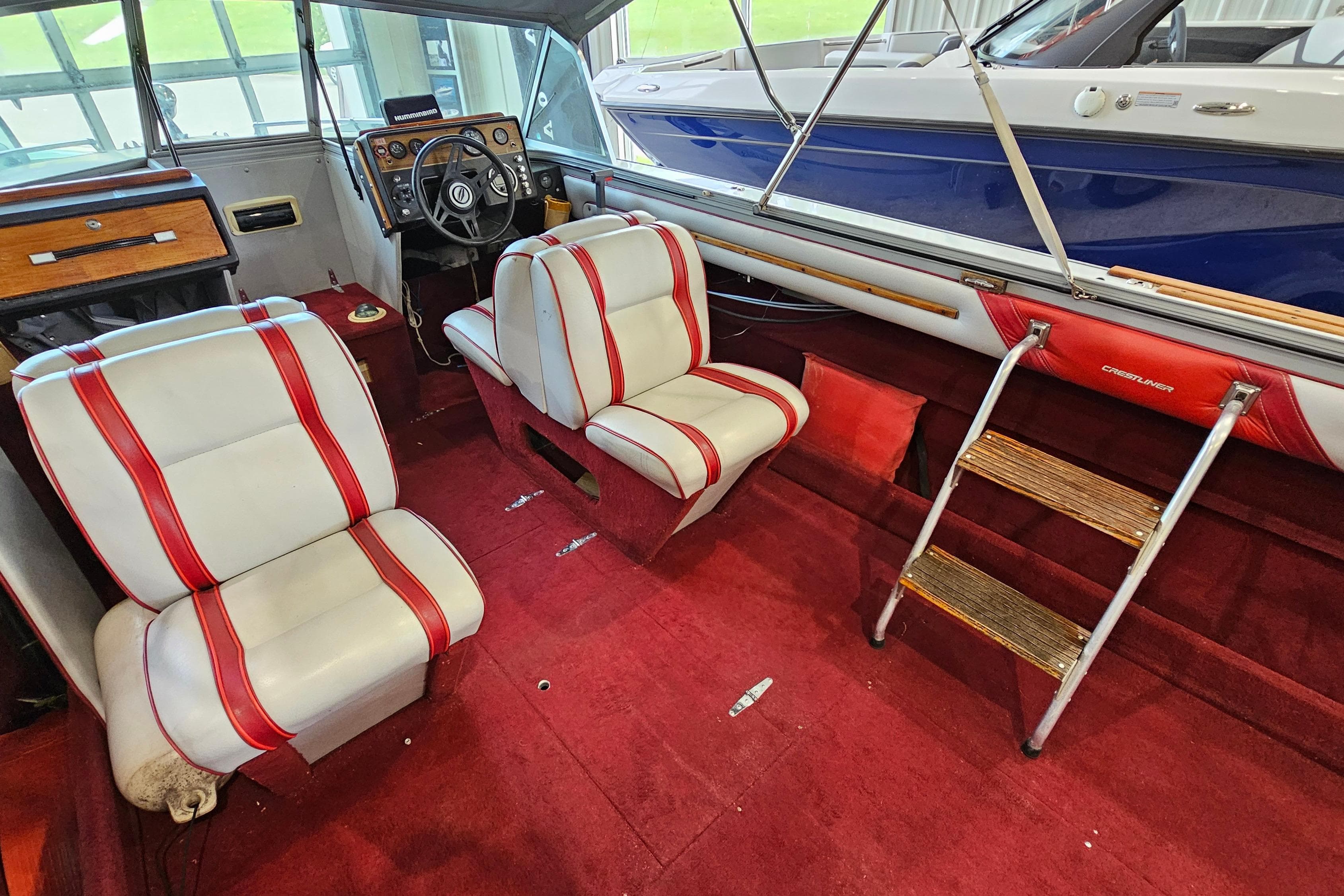 1988 Crestliner 2281 boat interior with red and white seats, wooden accents, and steering wheel.