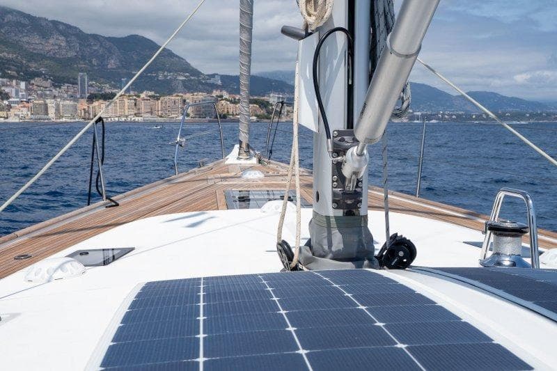 2023 Hallberg-Rassy 50 yacht deck with solar panels, sailing near coastal city.