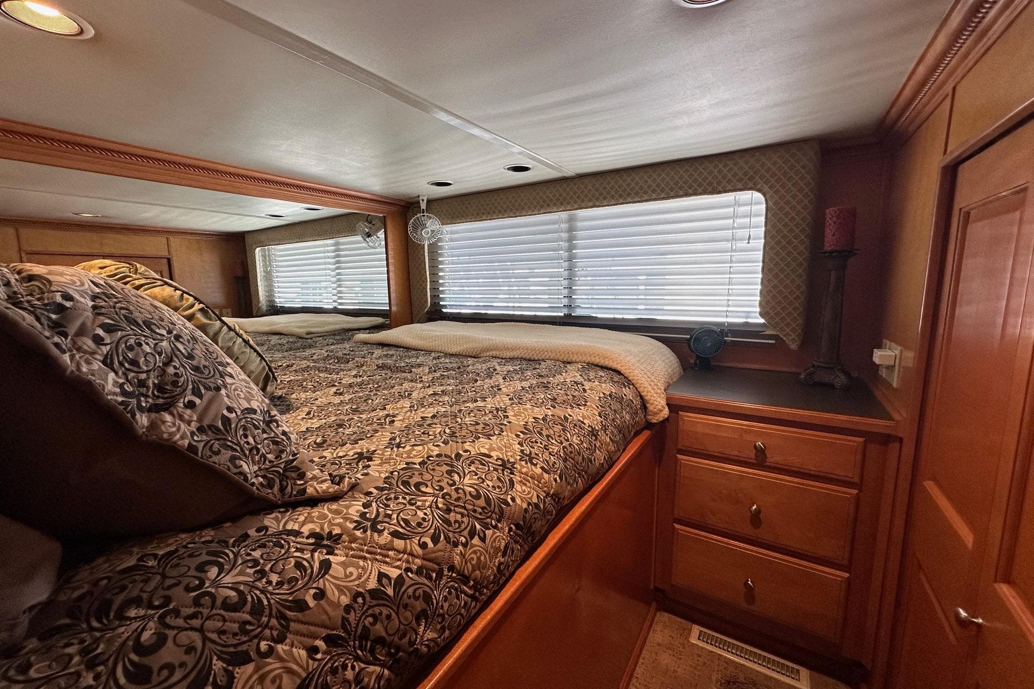 Luxurious bedroom interior in a 2004 Sumerset 18x96 houseboat with elegant bedding and wood cabinetry.
