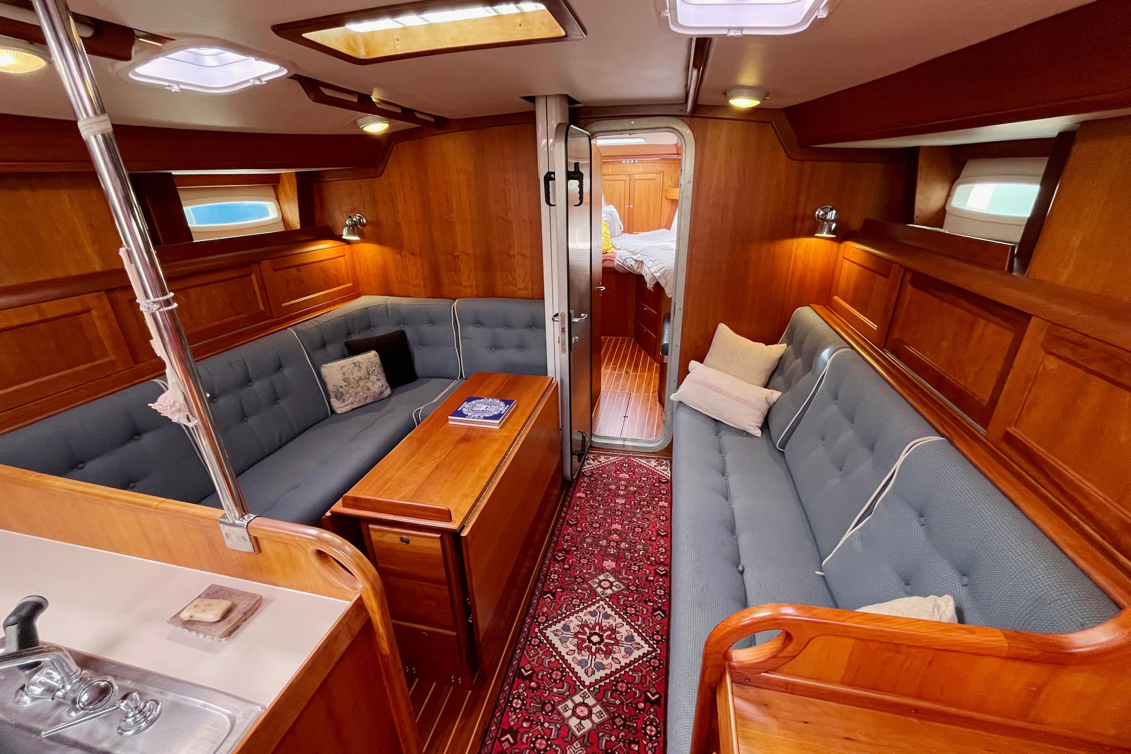 Luxurious 1995 Able Apogee 50 yacht interior with wooden paneling and cozy seating.