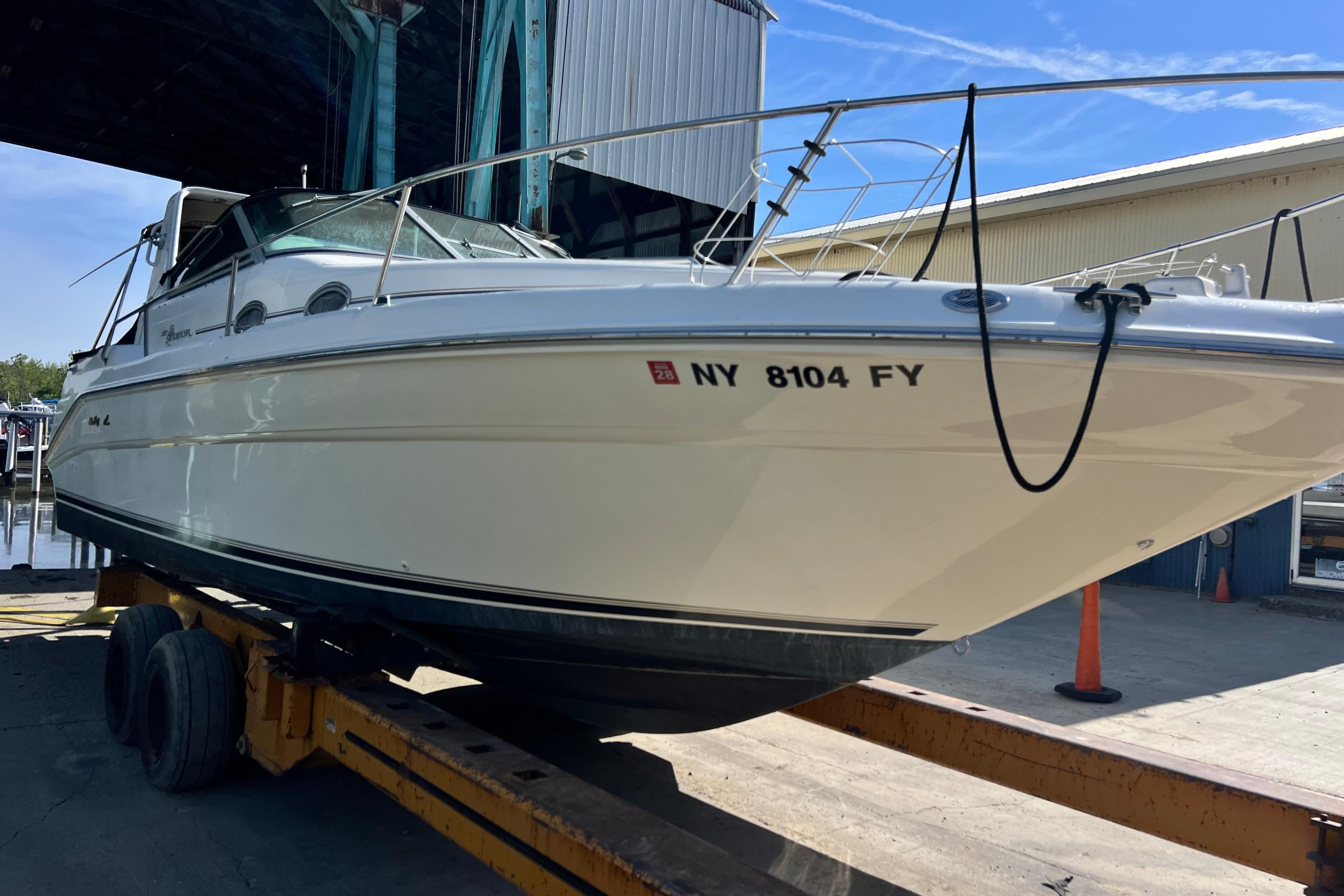 1996 Sea Ray 290 Sundancer boat on trailer in marina setting.