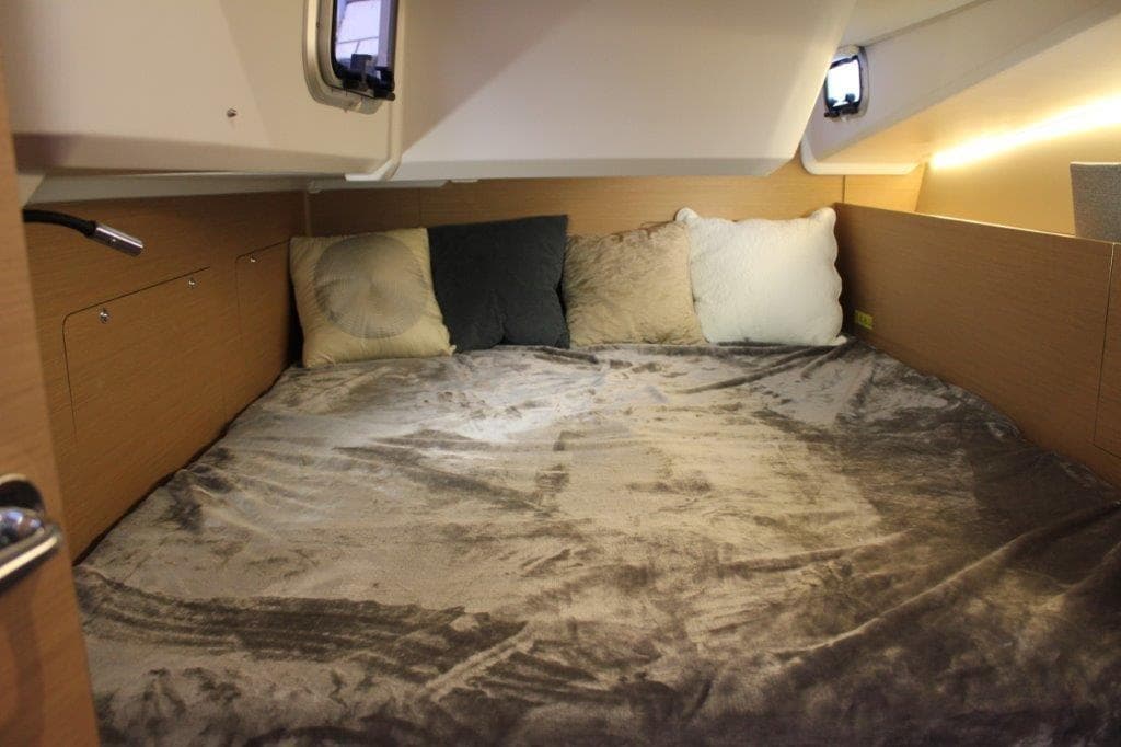 Cozy cabin interior of 2024 Jeanneau Sun Odyssey 490 with plush bedding and pillows.