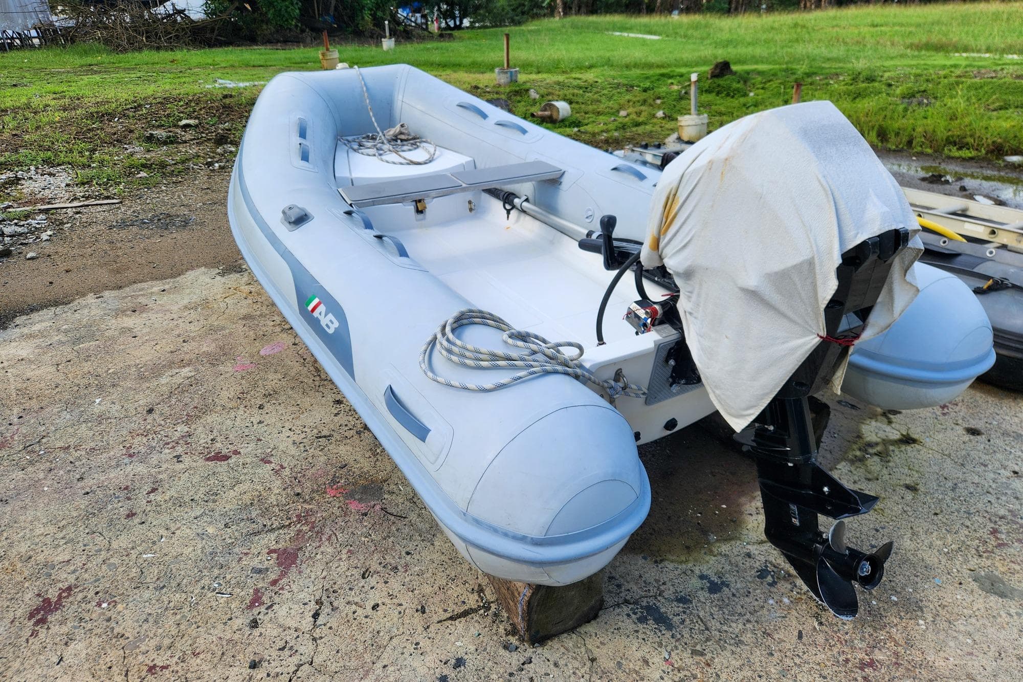 2022 Antares Hybrid inflatable boat with outboard motor, parked on concrete near grassy area.