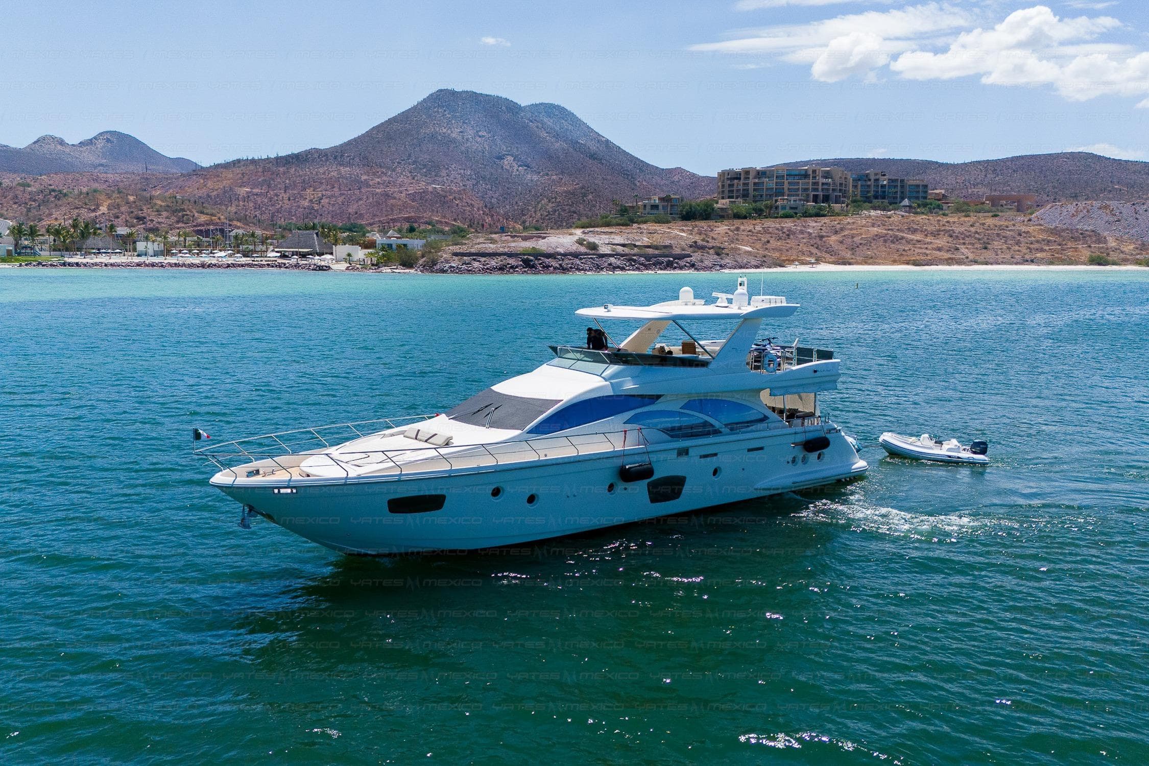 Luxury 2009 Azimut 75 yacht cruising in scenic coastal waters with mountainous backdrop.