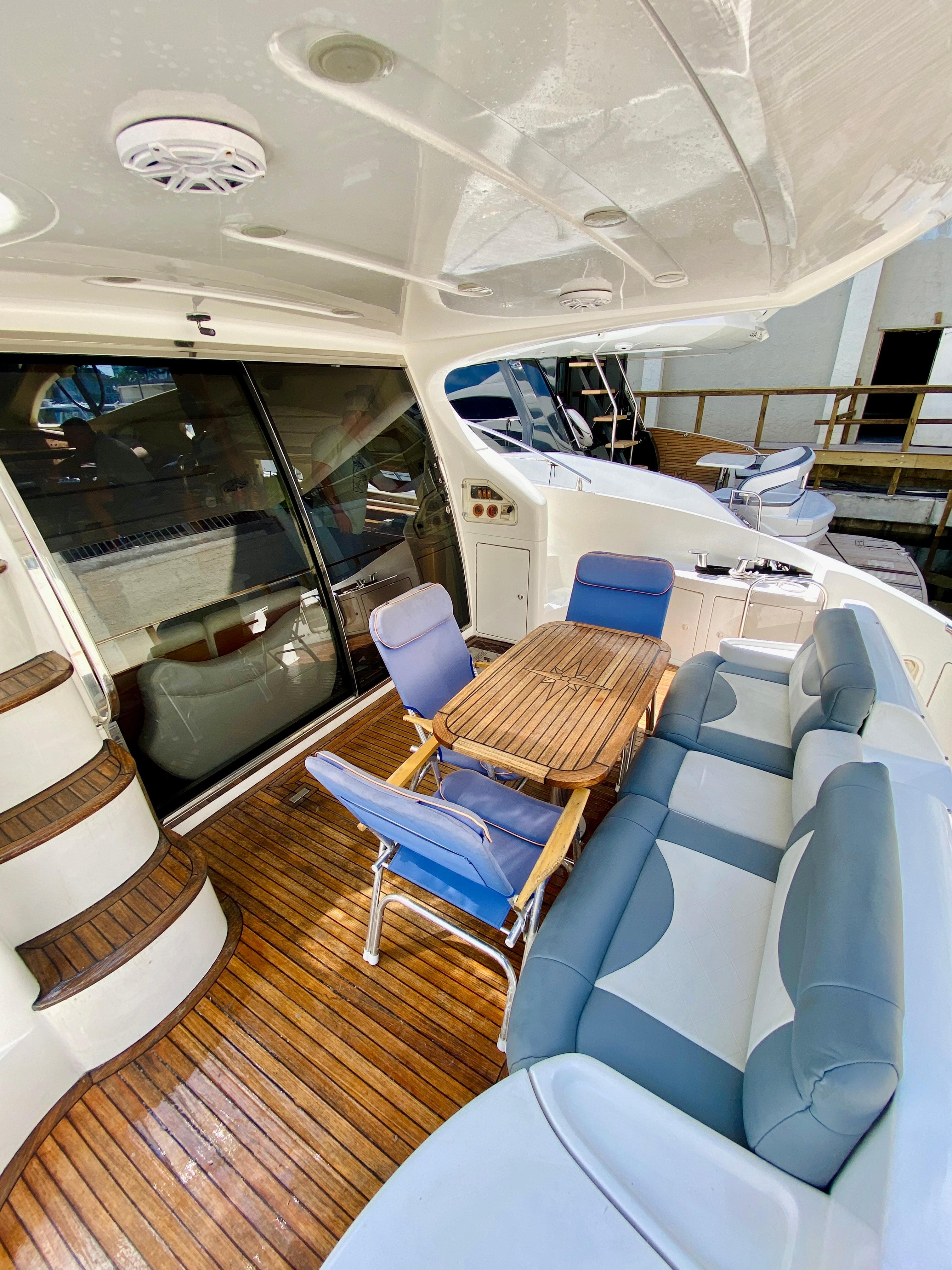 2002 Azimut 55 yacht interior with wooden deck, seating, and table.