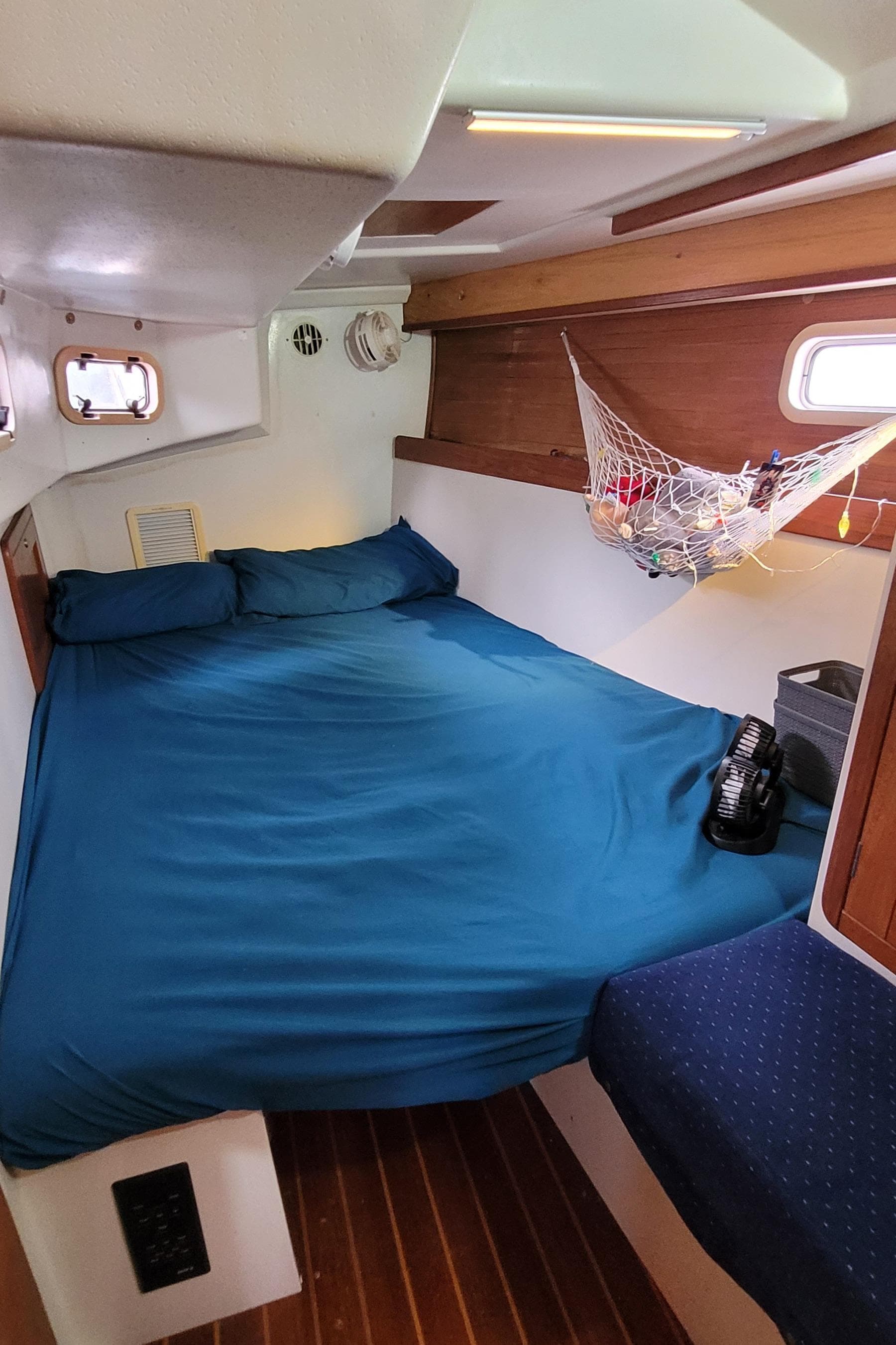 Cozy cabin interior of 1992 Catalina 42 sailboat with blue bedding and wooden accents.