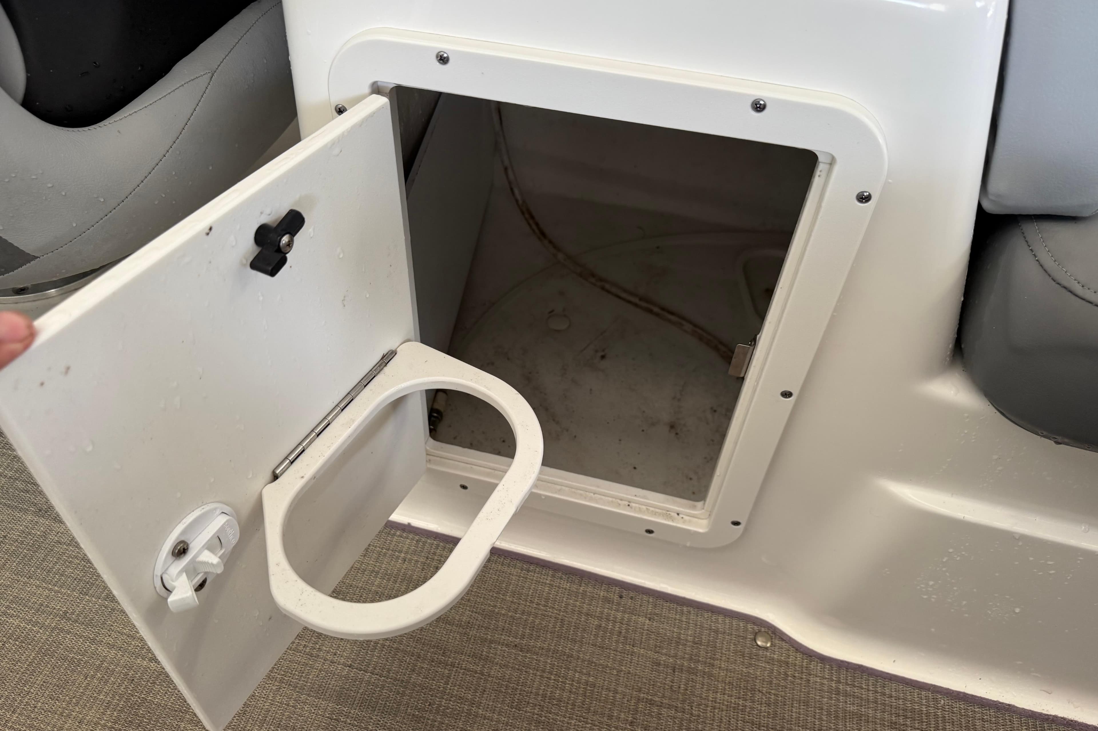 Open storage compartment on 2023 NauticStar 243 DC boat with cup holder.
