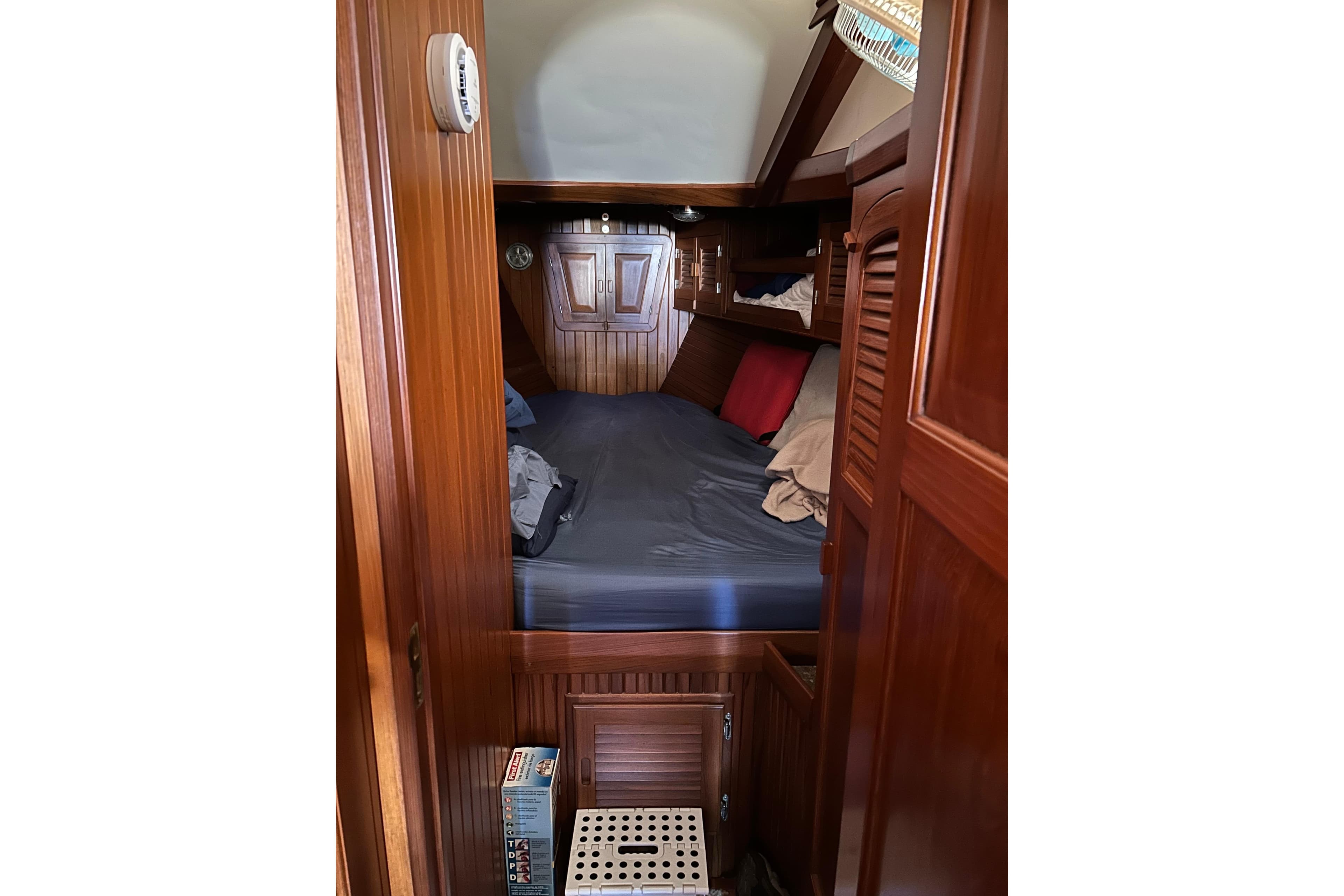 Cozy cabin interior of 1984 Slocum 43 sailboat with wooden paneling and bedding.