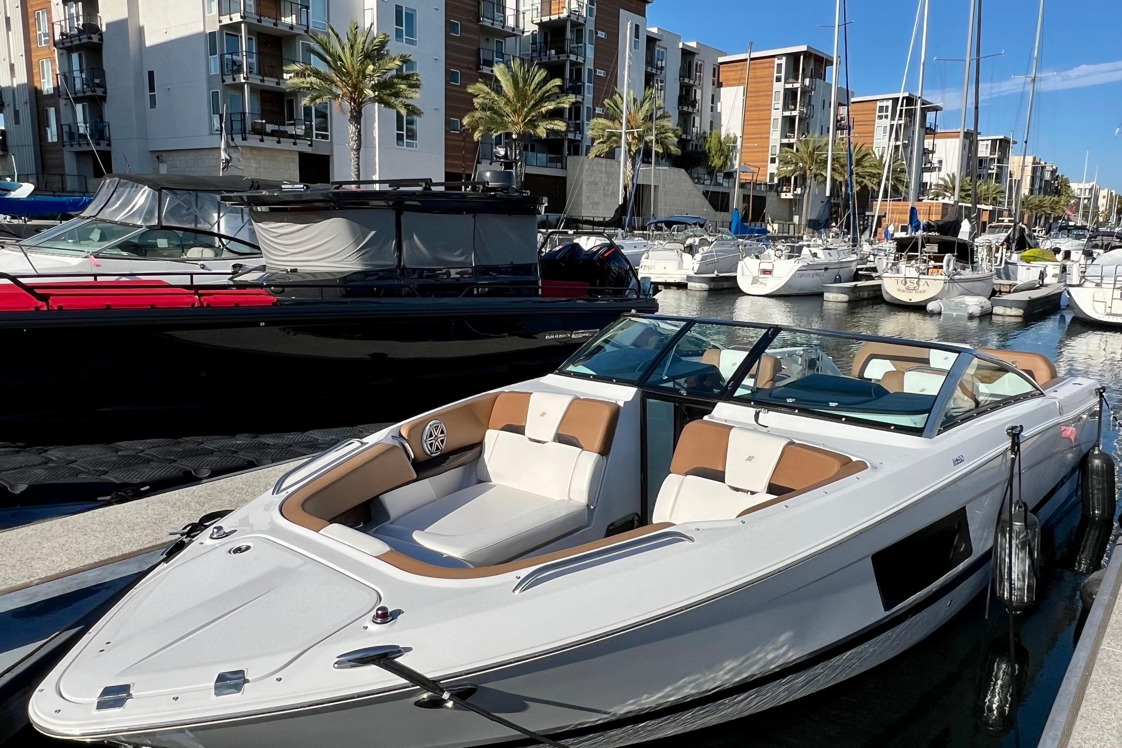 2019 Four Winns Horizon H290 boat docked in a marina with modern buildings.