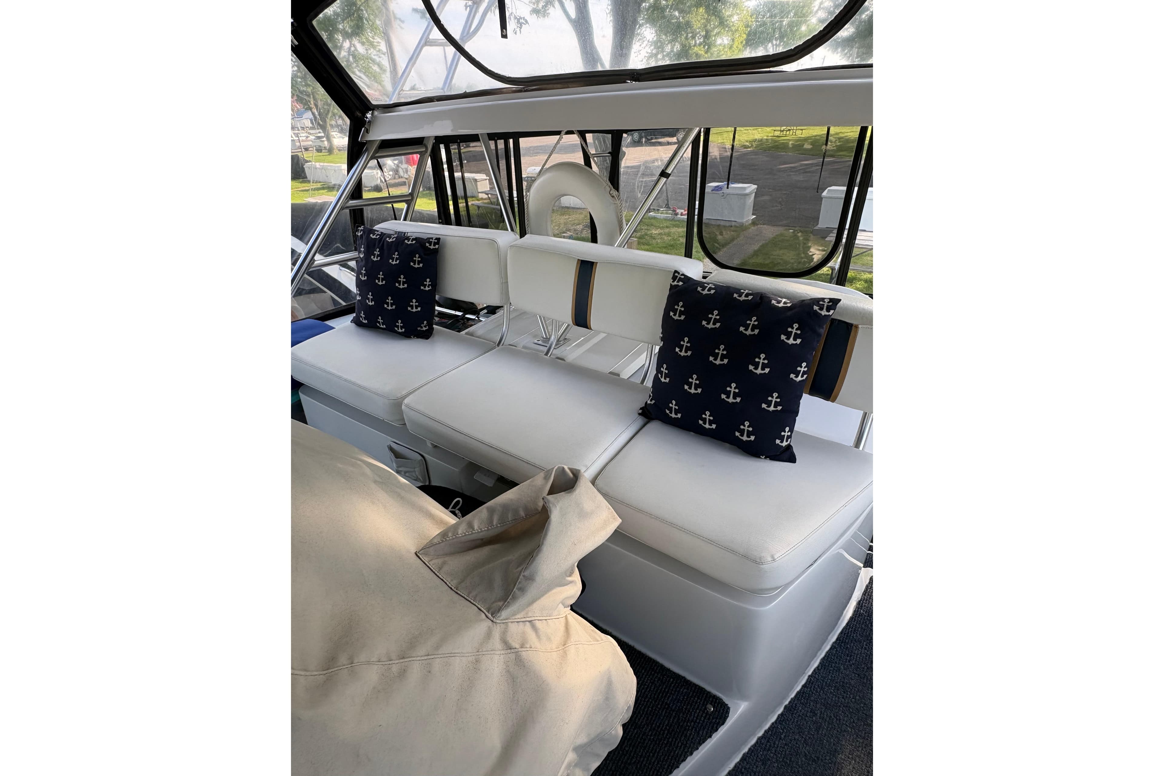 1997 Mainship 34 Motor Yacht interior with white seating and anchor-themed pillows.