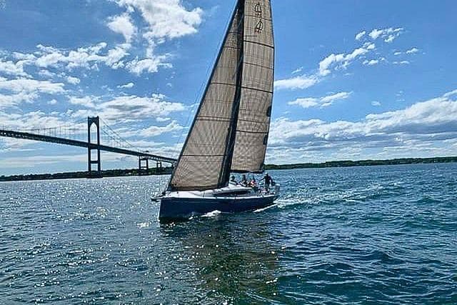 2019 Dehler 34c sailboat cruising near a bridge under a clear blue sky.