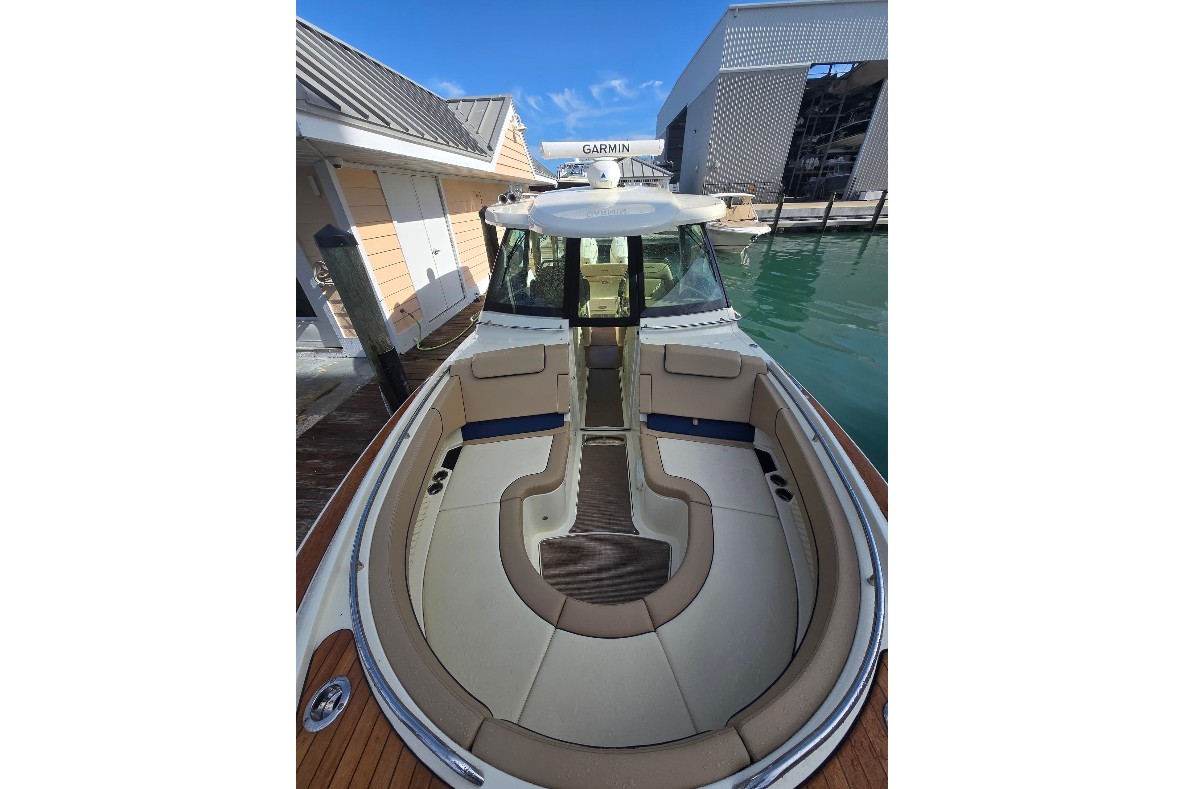 2023 Chris-Craft Calypso 35 boat with elegant seating, docked near modern buildings.