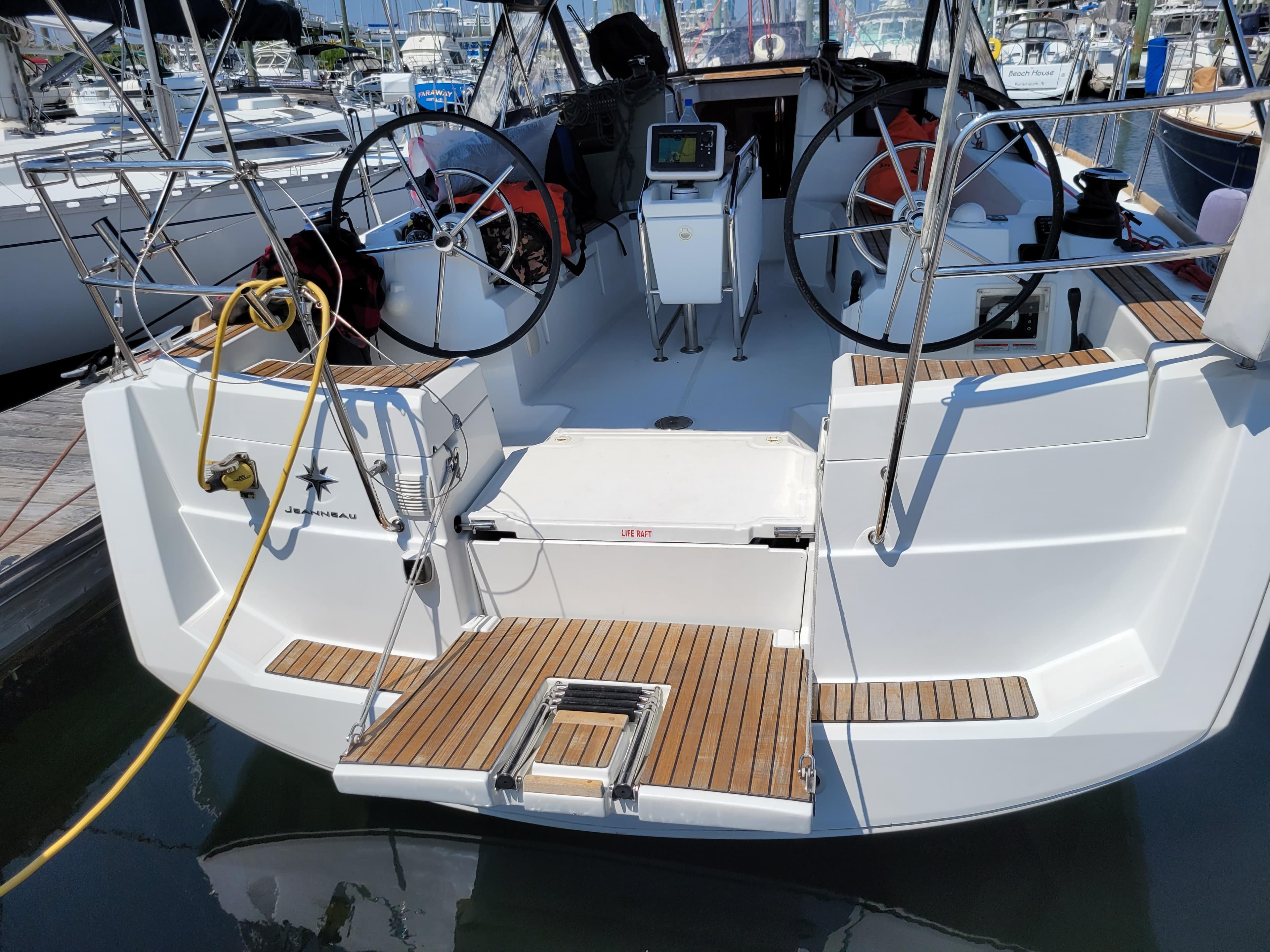 2016 Jeanneau 379 sailboat with dual steering wheels and teak deck in a marina.