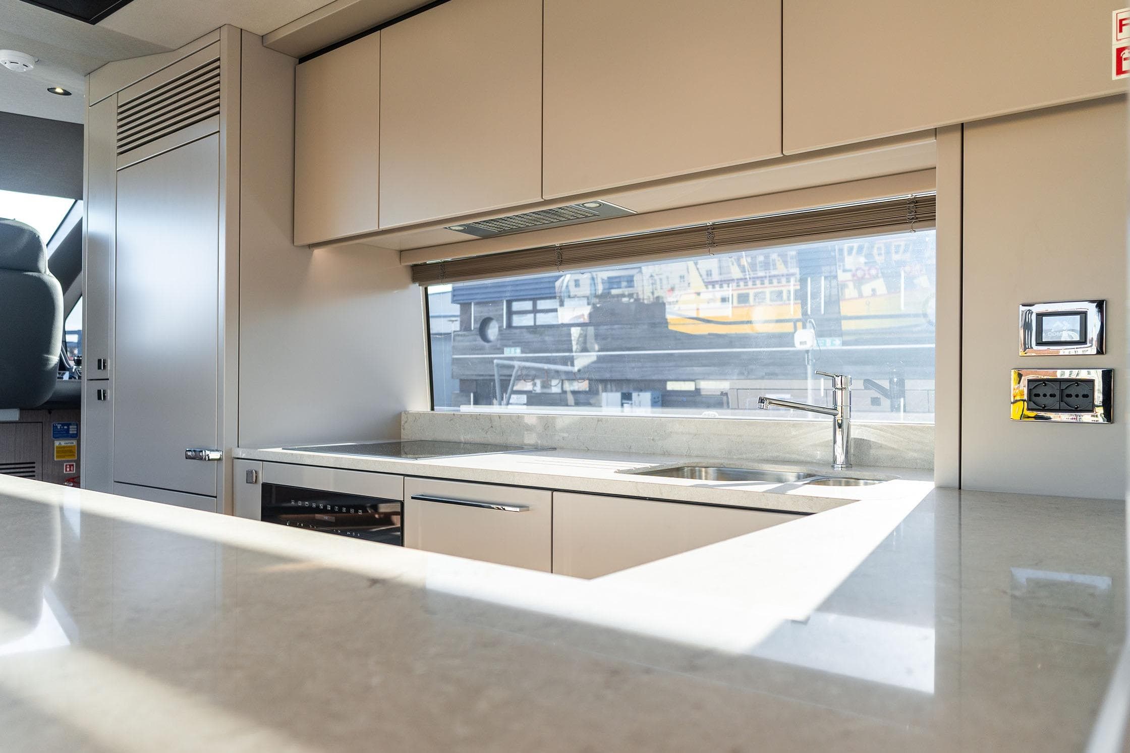 Modern kitchen interior of 2026 Sunseeker 76 Yacht with sleek countertops and large window.