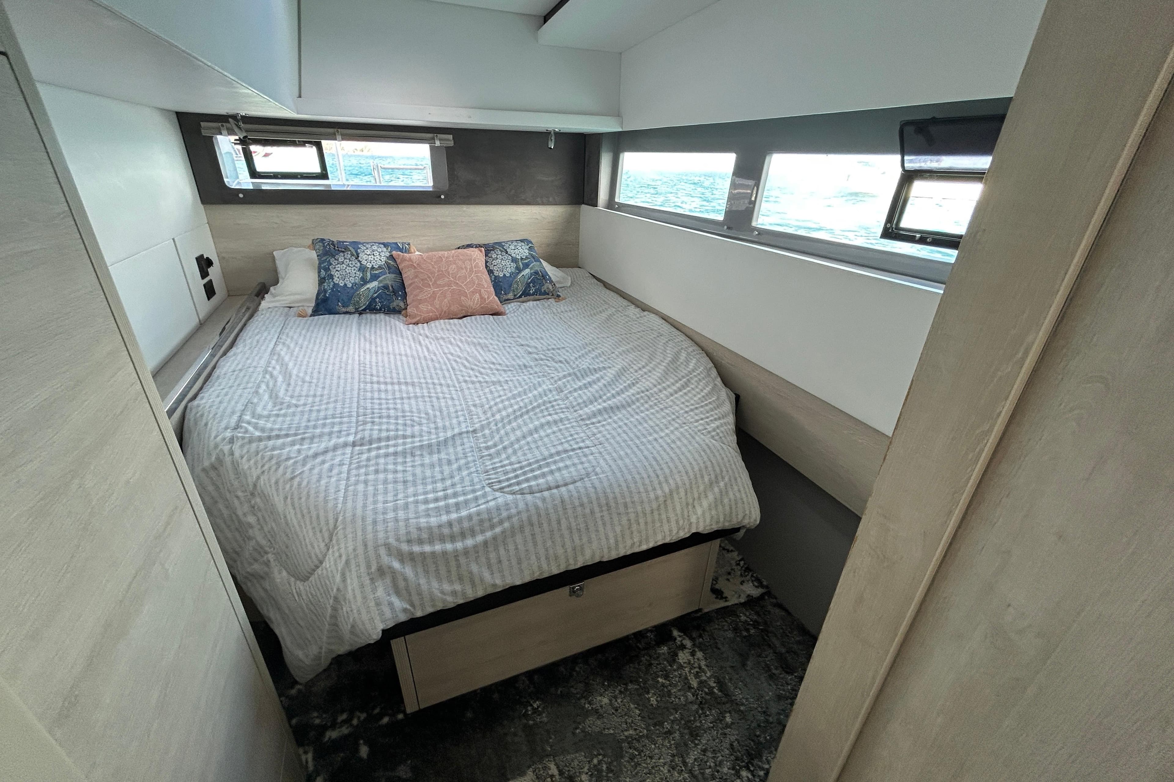 Cozy bedroom in a 2020 Leopard 45 yacht with ocean view windows.